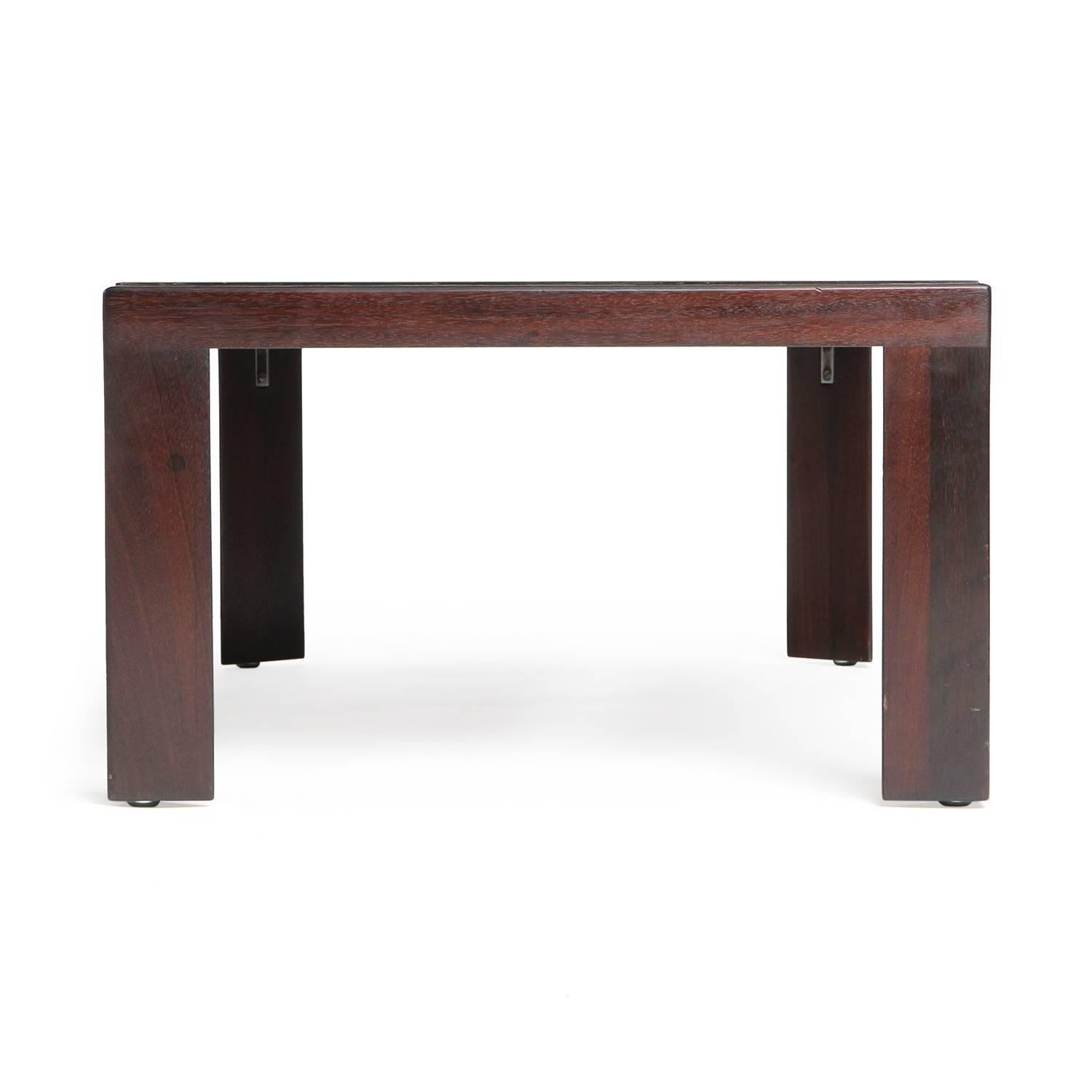 A rectangular dark walnut low table having a black laminate top and distinctive triangular legs.