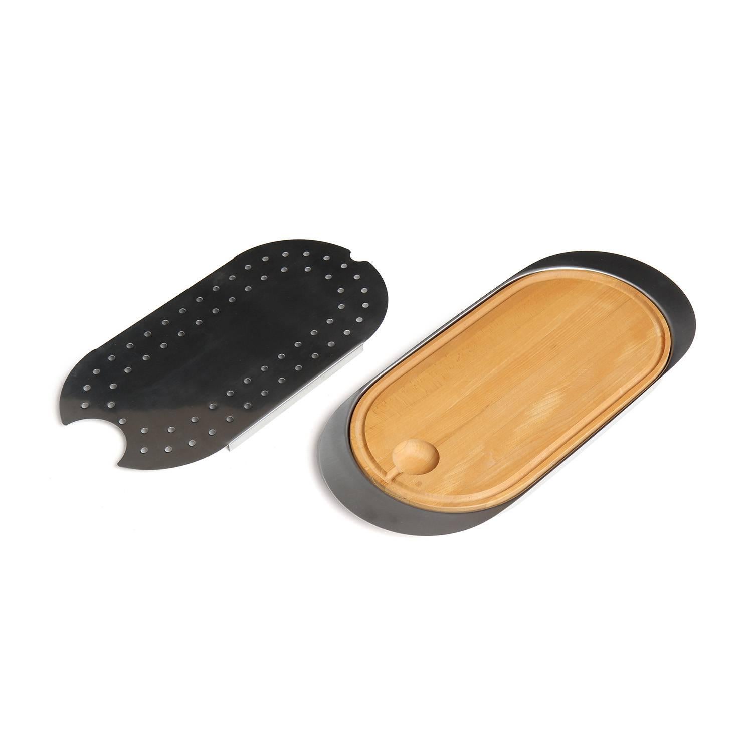 A masterfully crafted, multifunctional minimalist oval serving and cutting board in polished stainless steel having and inset wooden board and a removable perforated steel cover.