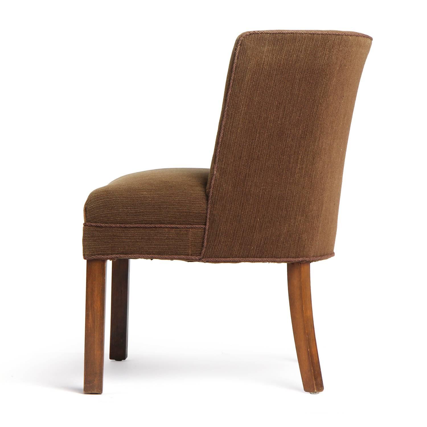 A stately and well proportioned armless upholstered side chair having a curved back, floating on substantial squared walnut legs.