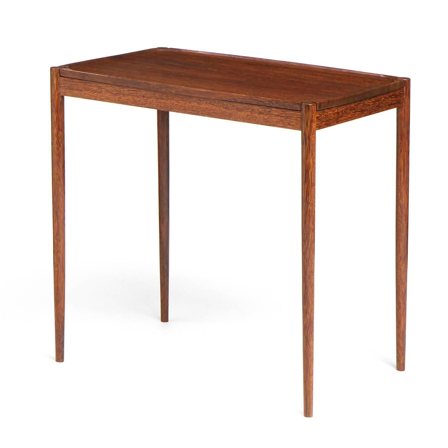 A spare and elegant tropical hardwood occasional table having a rectangular top and slightly tapered dowel form legs.