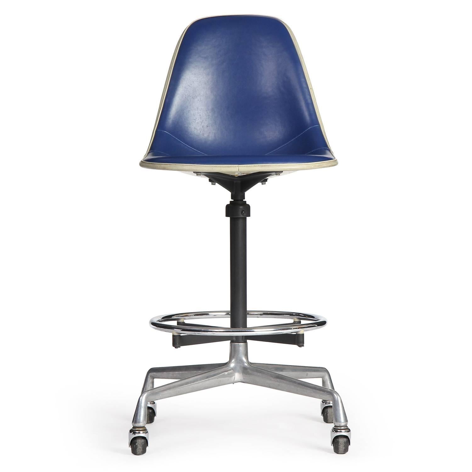 A graphic and adjustable swiveling tall armless task chair on an early four pronged base with casters, having a floating circular foot rest.