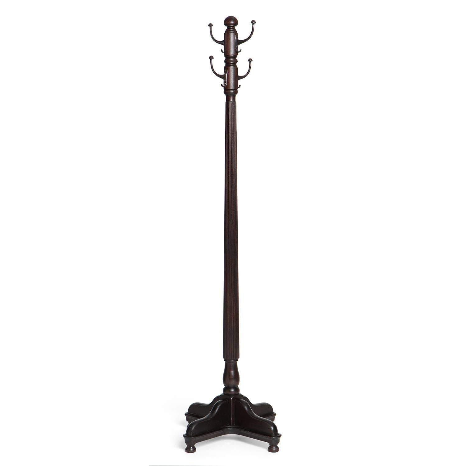 A stately and well scaled lathe turned ebonized walnut coat tree having a tapering fluted stem with four hooks rising from a scalloped cruciform base.