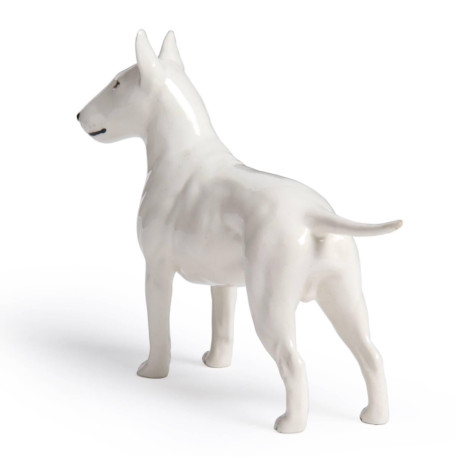 A finely modeled glazed ceramic figurine depicting an alert Bull Terrier.