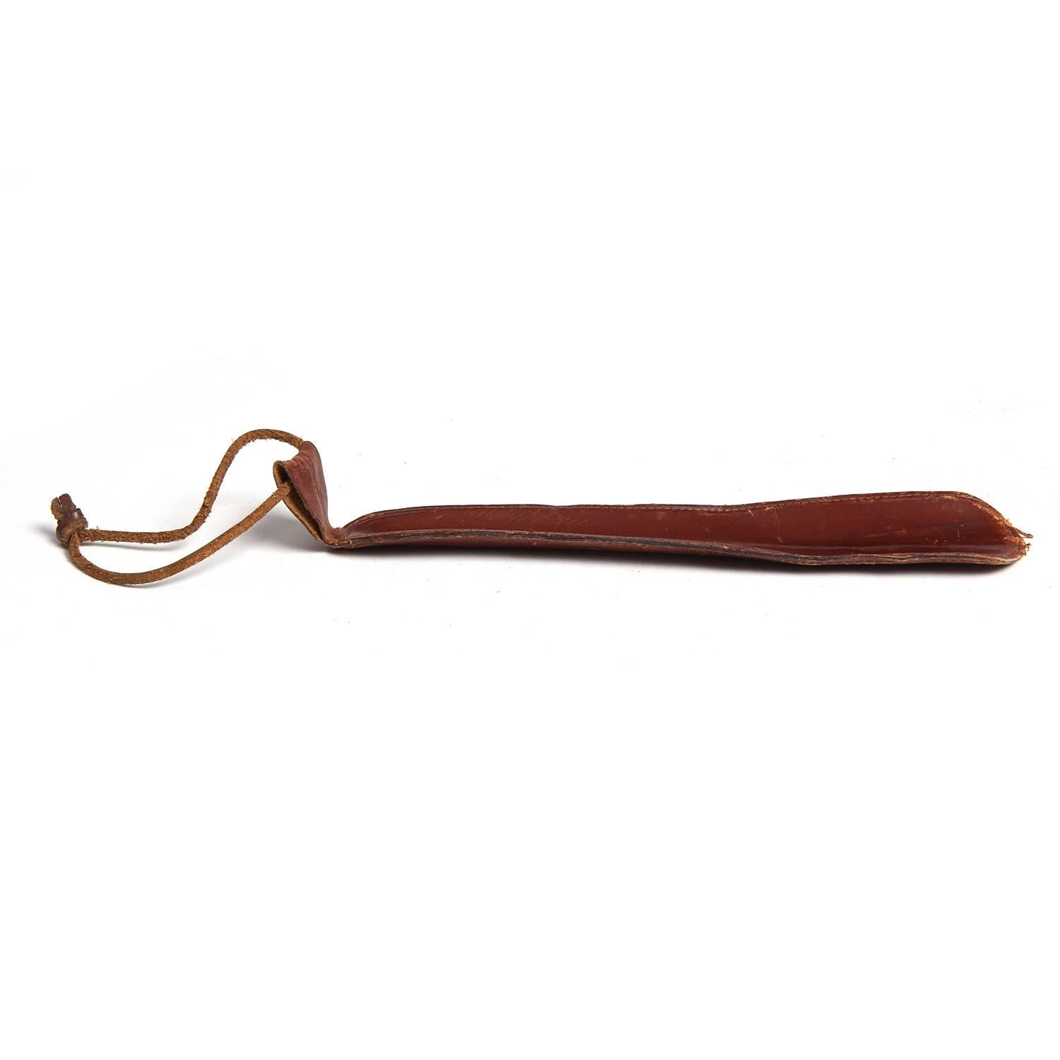 A fine leather wrapped and hand-stitched shoe horn with a leather cord hanging strap.