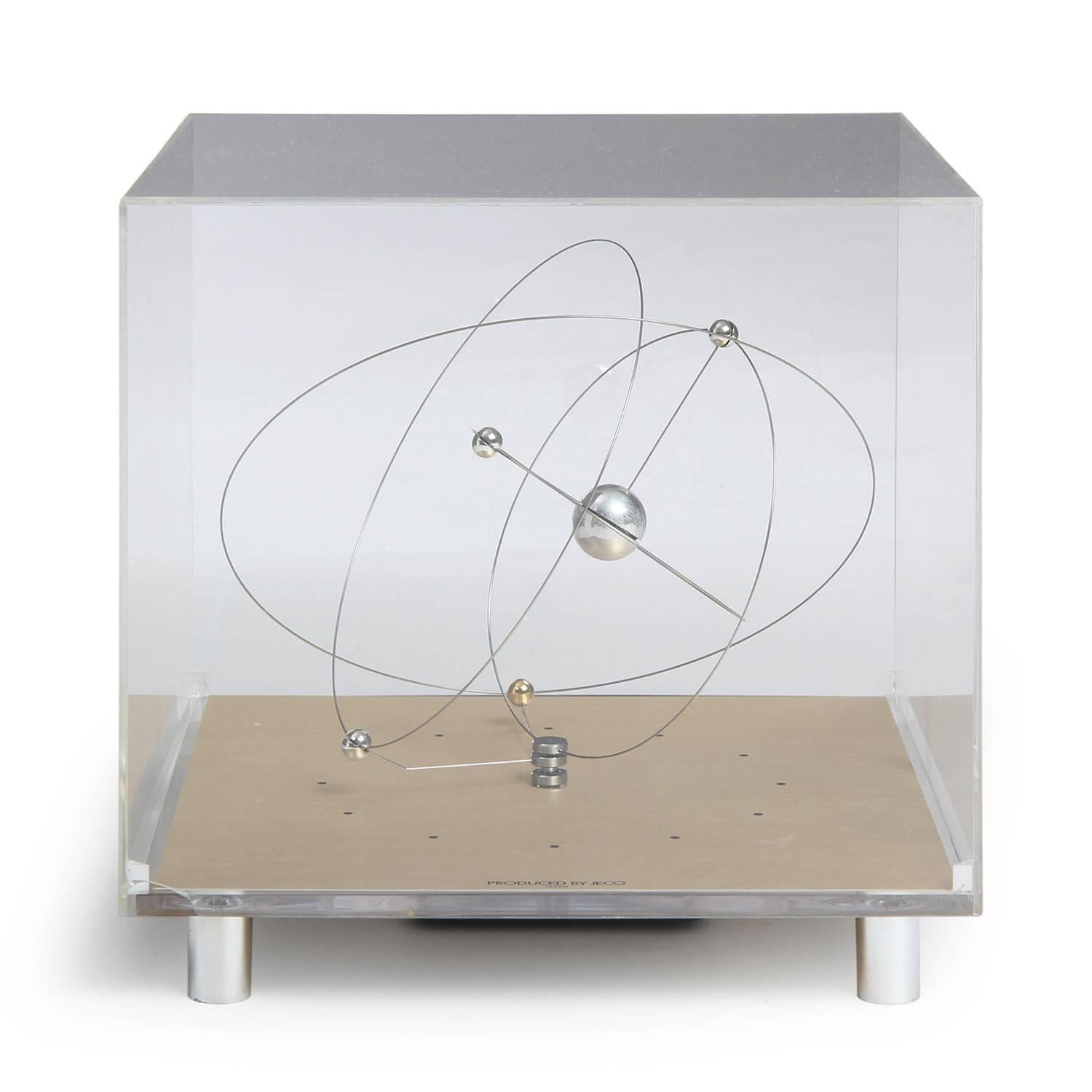 An unusual and highly innovative space age clock having rotating and orbiting stainless steel rings and orbs encased in a  lucite cube marking the passing of time.
