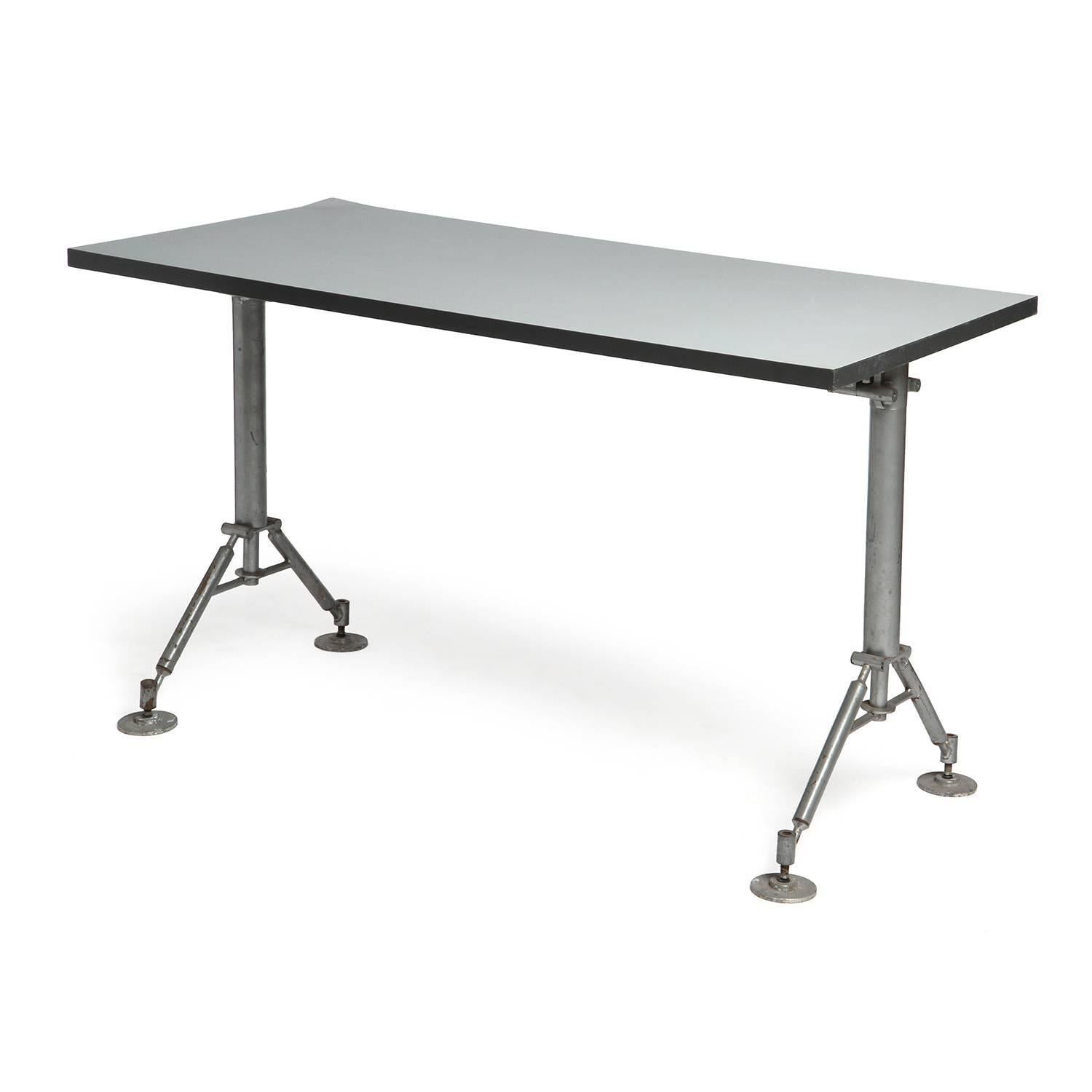 A work table having a steel frame with splayed legs and steel disc feet supporting a floating rectangular top.