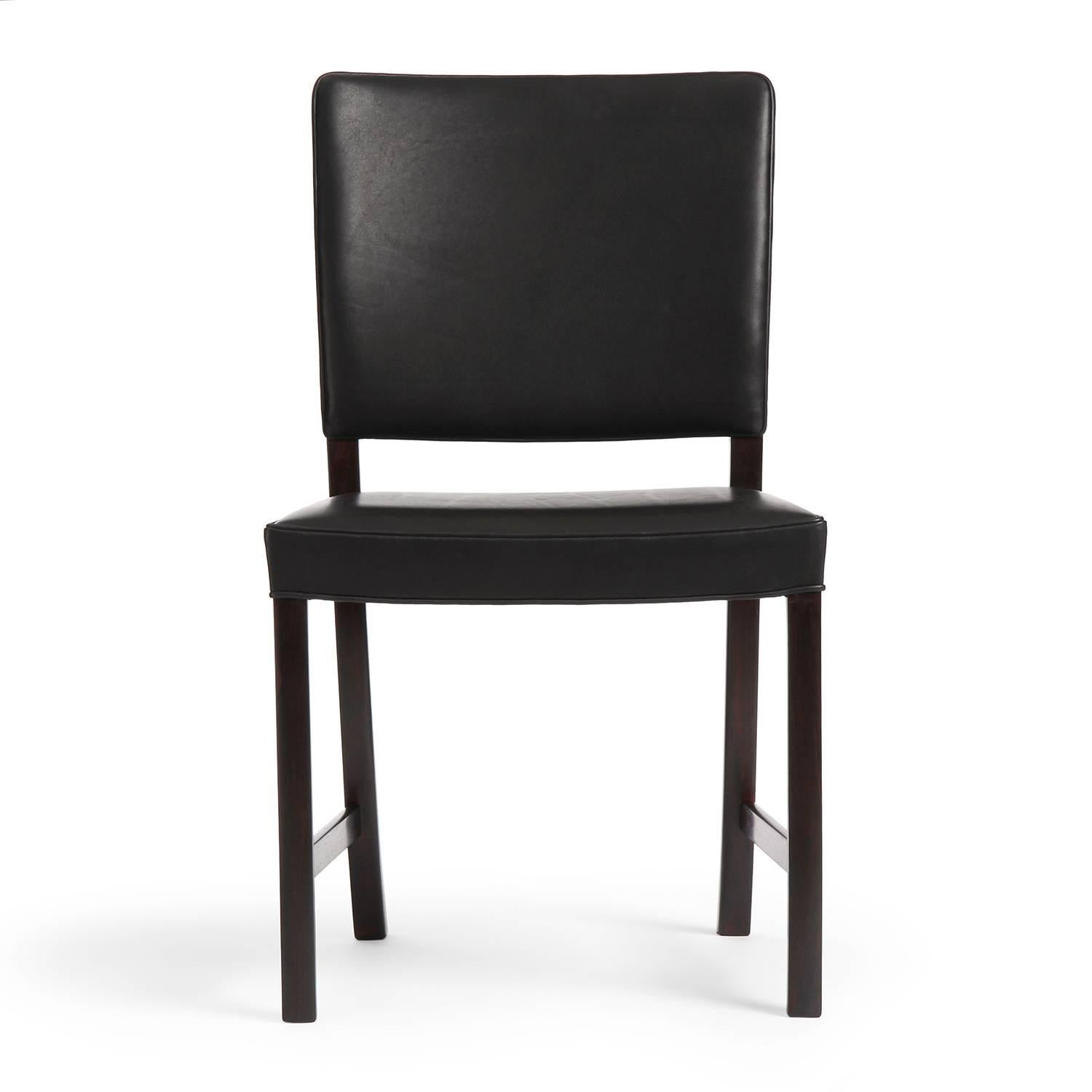 A refined and elegant dining chair having spare Brazilian rosewood frames and oiled black leather upholstery.