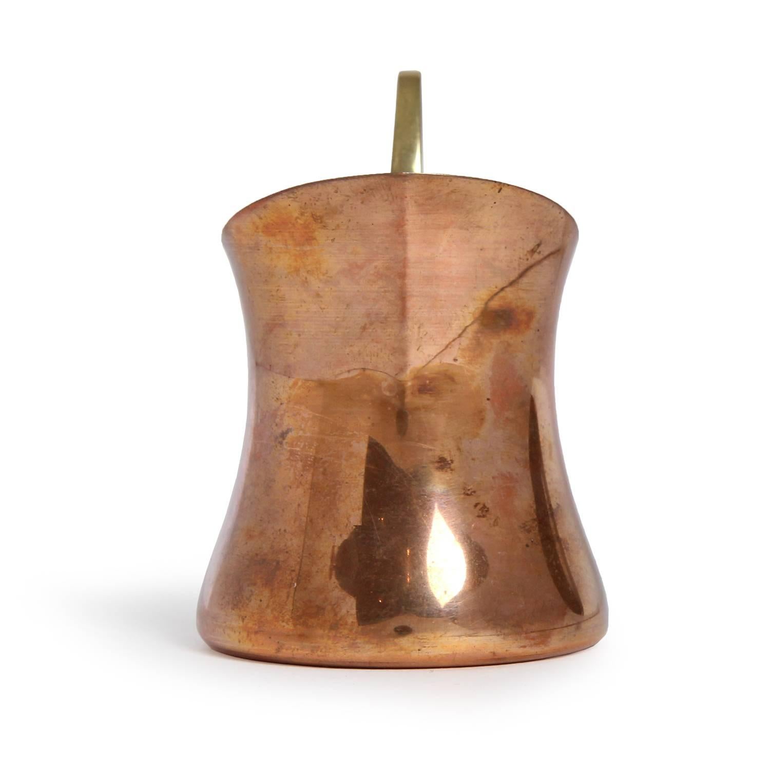 A small and sculptural creamer in copper and bronze having a bias cut form with dramatic swooping handle.