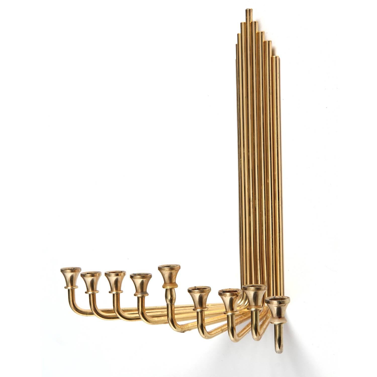 A Mid-Century Modern wall hanging menorah crafted of conjoined radiating brass plated steel rods. Made in the USA, circa 1970s.