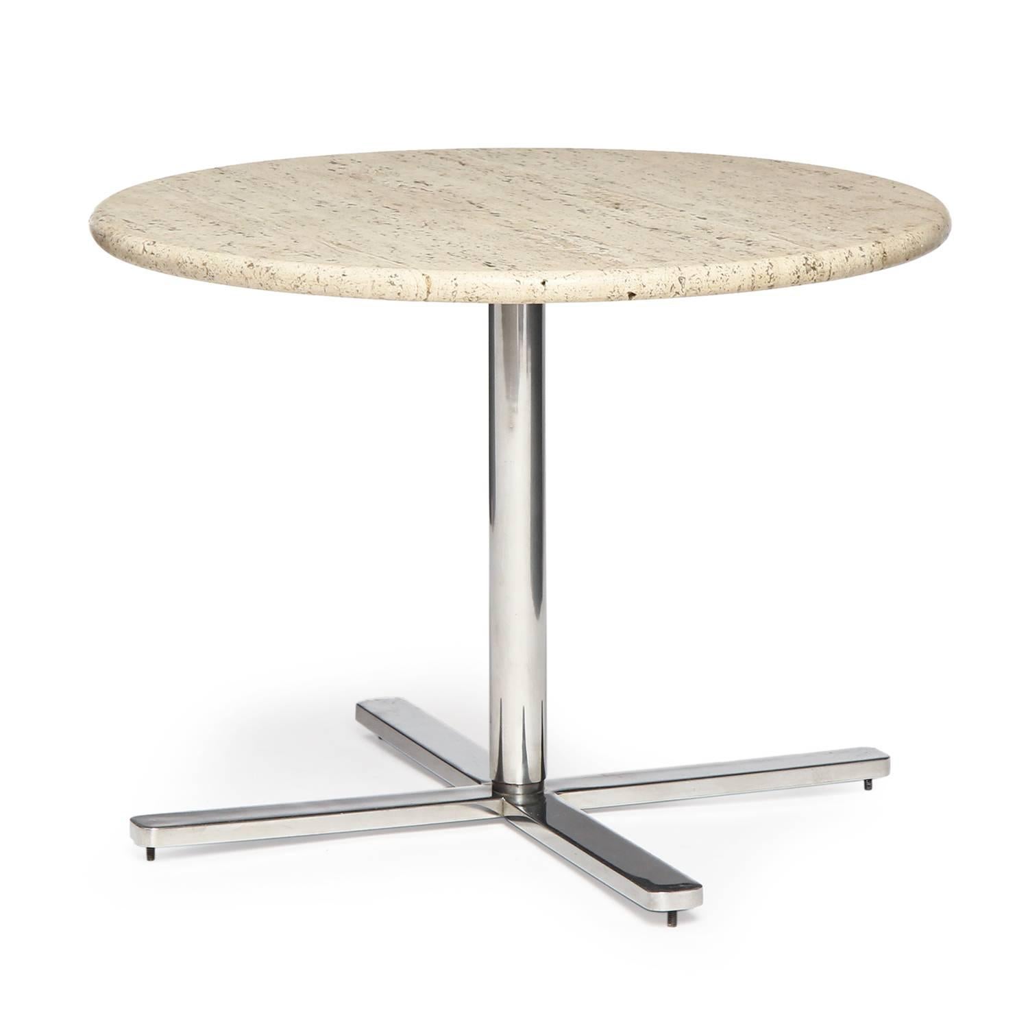 A spare and architectural pedestal table having a substantial chromed steel base supporting a round bevel-edged travertine marble top.
