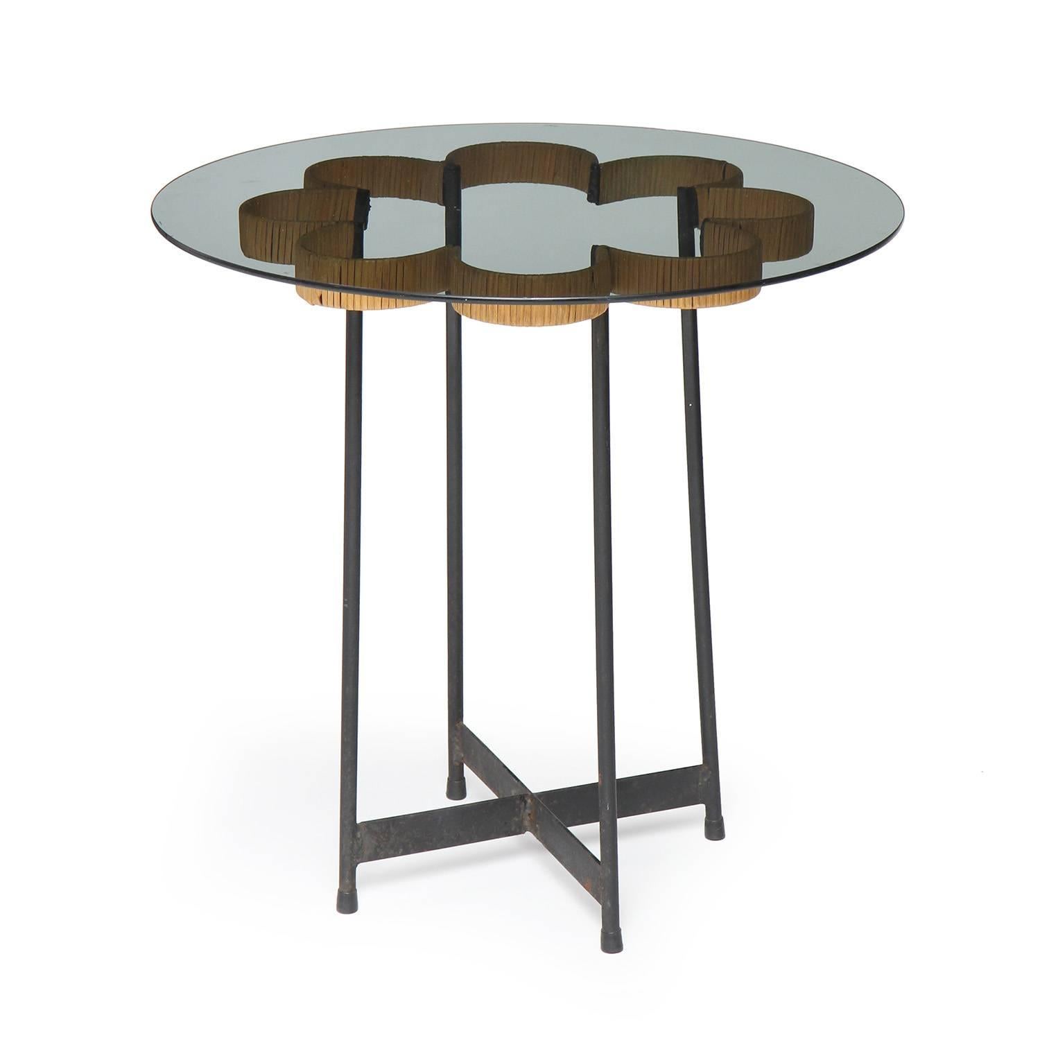 Une table d'appoint en verre, expressive et peu commune, ayant la forme de huit boucles conjointes en rotin flottant sur une structure architecturale en x.