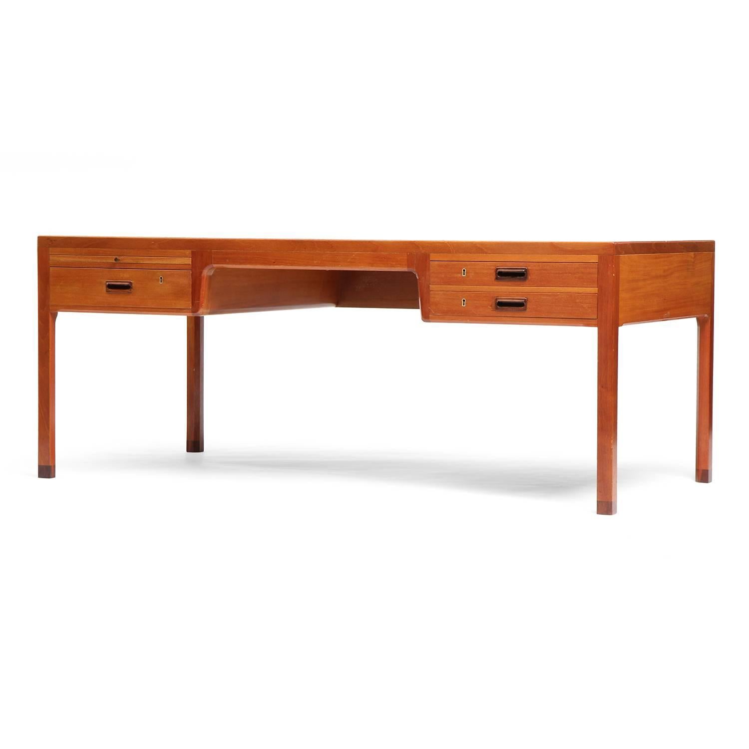 A superb, generously scaled and impeccably handcrafted desk in pale mahogany having a finely proportioned rectilinear form. The desk is fully finished on all sides; the drawers have carved recessed pulls and there is a retractable writing surface.