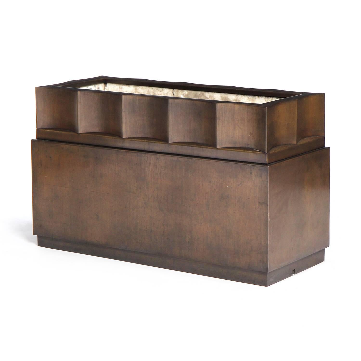 A stately, elegant and substantial planter finely crafted of patinated bronze, having a strong rectangular form with a recessed scalloped upper section.