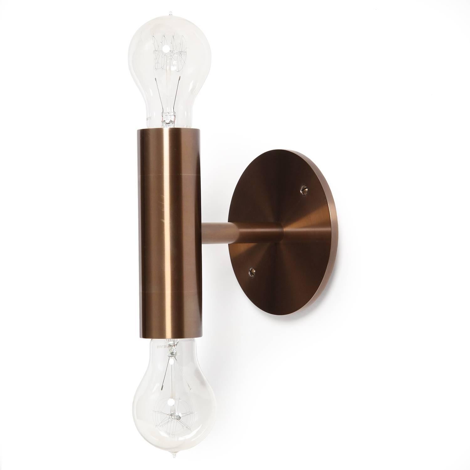A spare and impeccably rendered wall / sconce double light fixture made of solid brass. The fixture can be oriented vertically or horizontally. Available in polished, brushed, patinated or blackened finishes. Lead time 4-8 weeks. Made at the Wyeth