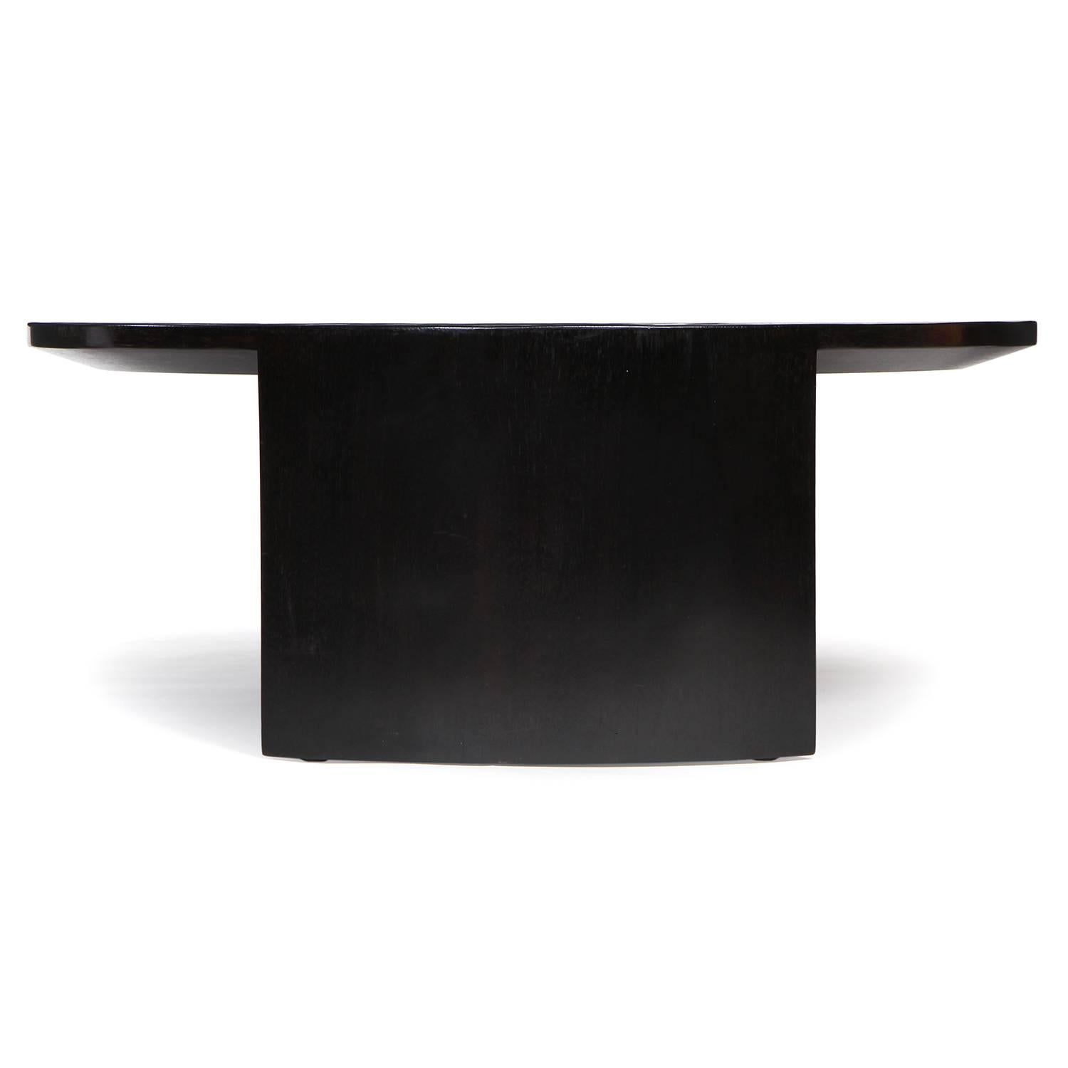 An impeccably rendered and beautifully proportioned custom split ebonized bamboo low table having a round top floating on a pair of curved and tapered slab legs.