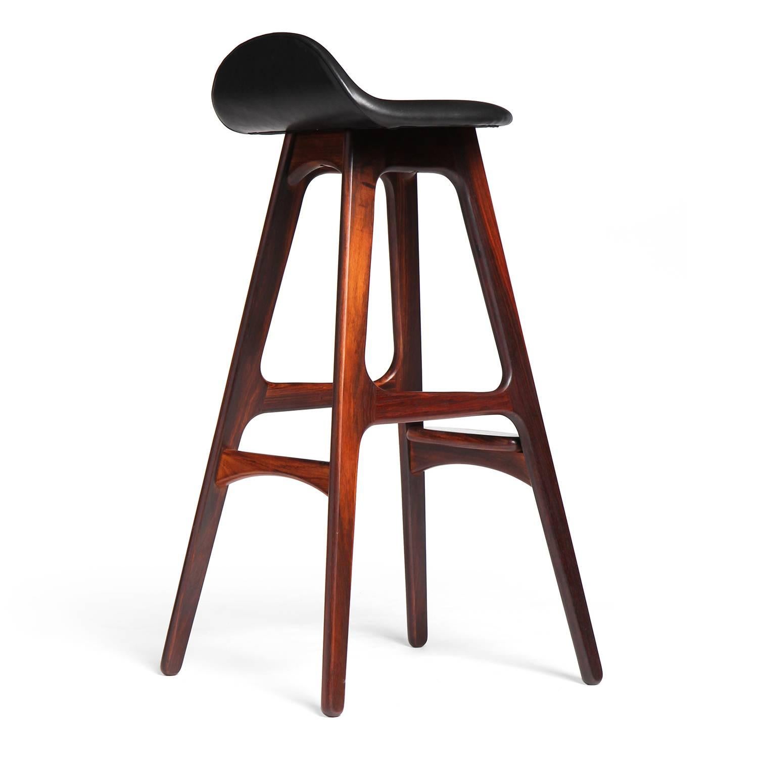 A sculptural and comfortable barstool having splayed legs, a  shaped seat with an upturned back support and a rounded projecting foot rest.