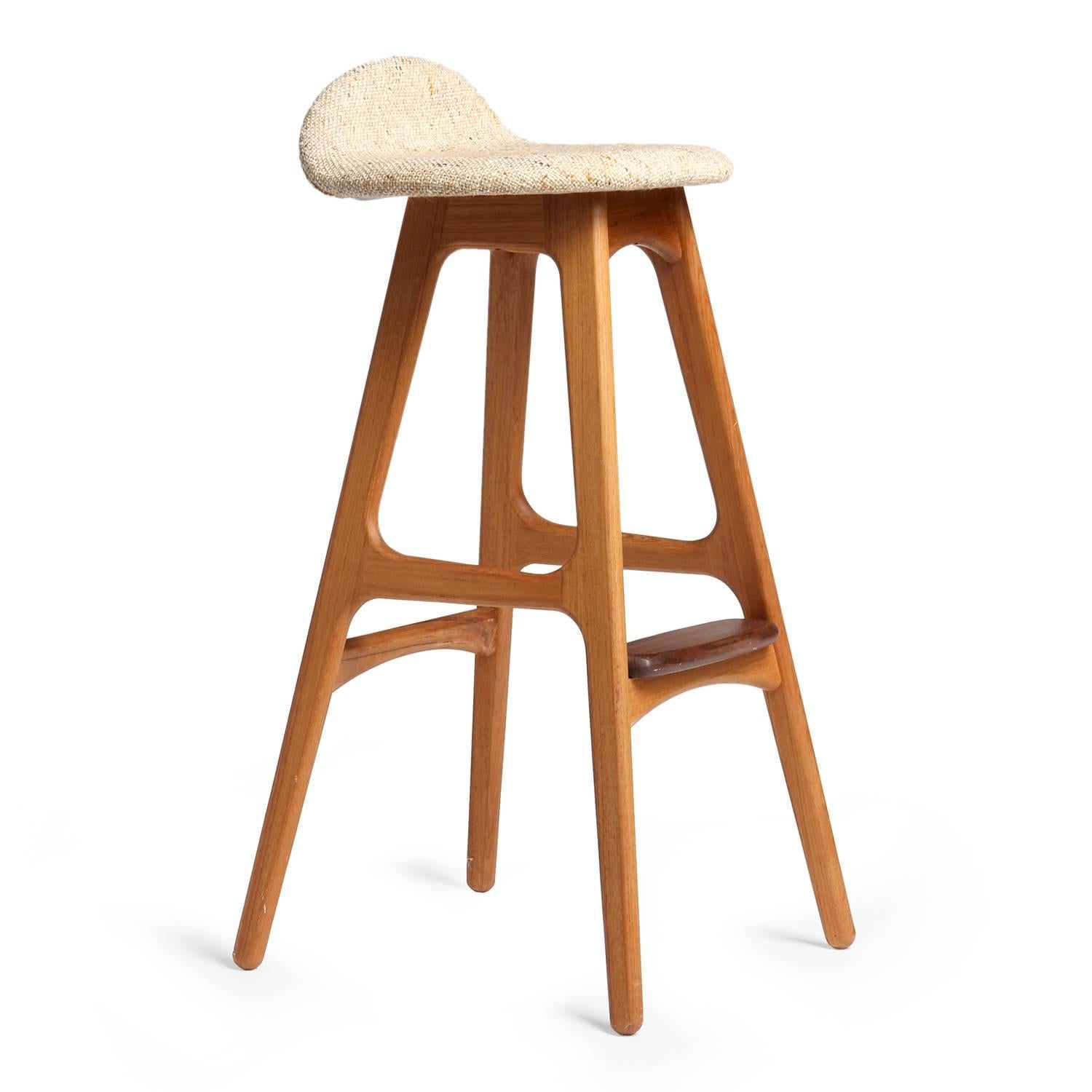 A sculptural and comfortable barstool having splayed legs, a shaped seat with an upturned back support and a rounded projecting foot rest.