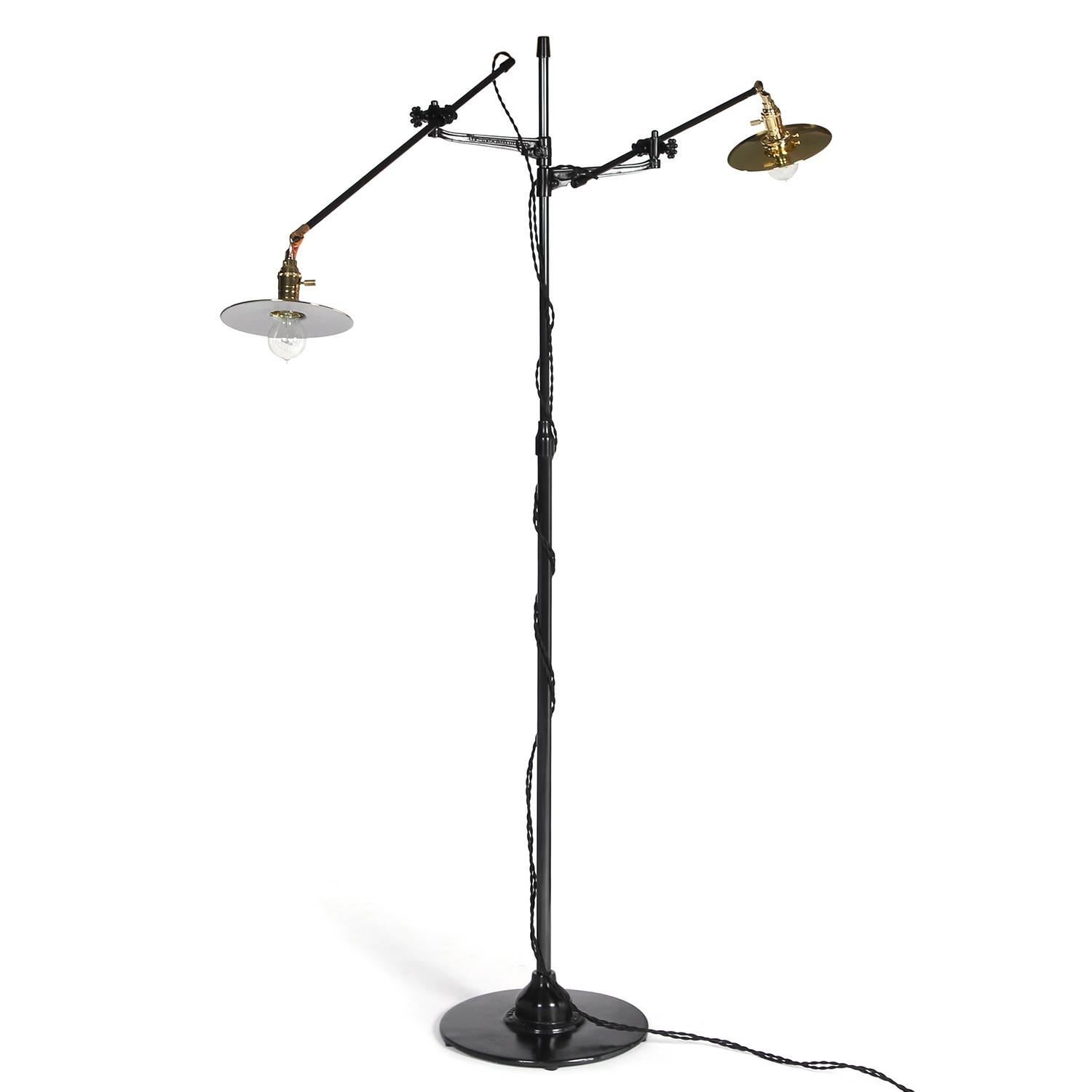An impressively scaled and finely fabricated floor lamp in patinated steel and polished brass having two articulating arms that also can be adjusted vertically, rising from a stepped disc base.