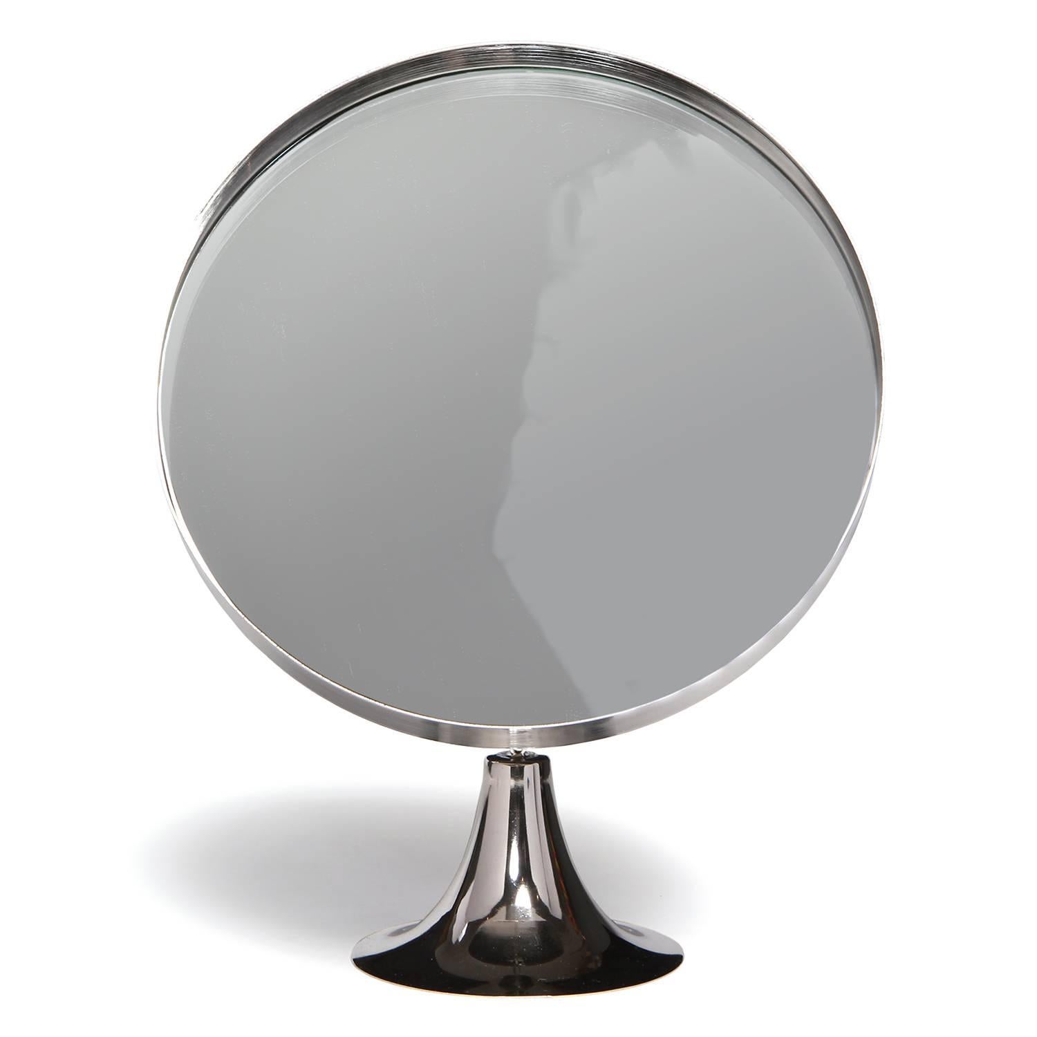 A Minimalist and refined table mirror in stainless steel having a sculptural pedestal base supporting a floating tilting mirror.