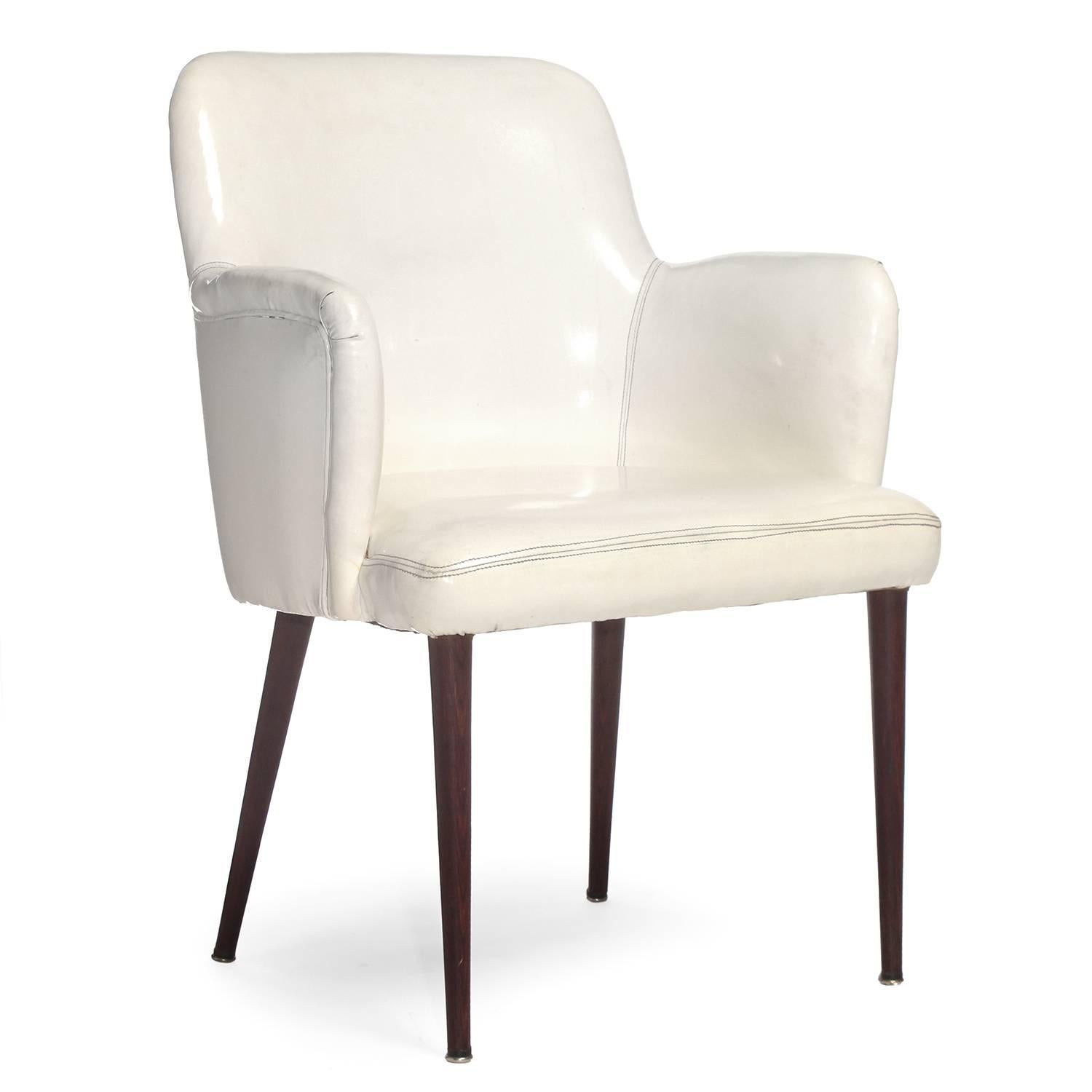 A tailored armchair having turned rosewood legs and retaining its original form-fitted white vinyl upholstery.