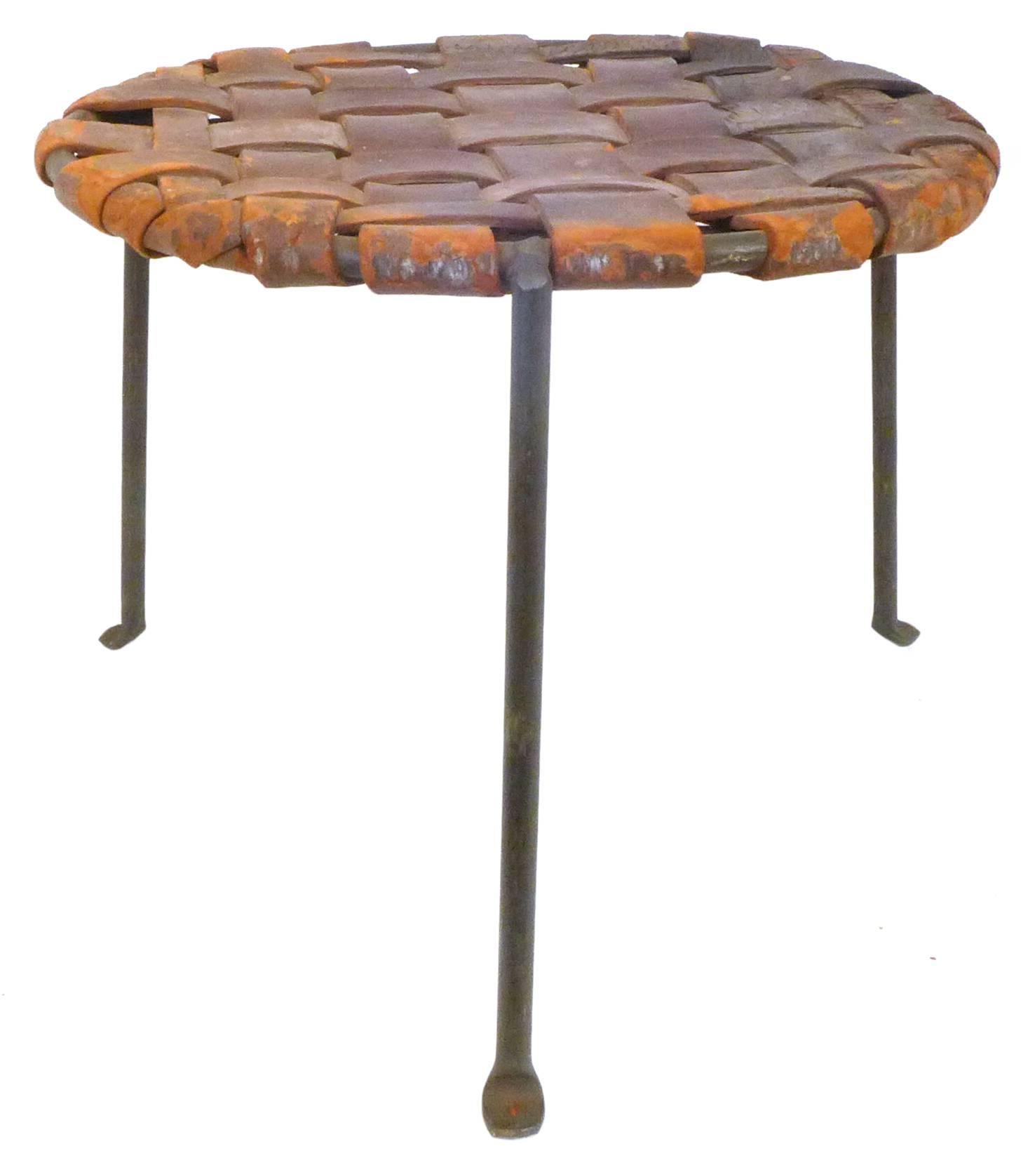 A handsome pair of wrought iron and woven leather stools by Lila Swift & Donald Monell. Beautifully simple, three-legged constructions with great, contrasting patinas; thick leather straps of assorted widths woven and tied underneath in an alluring,