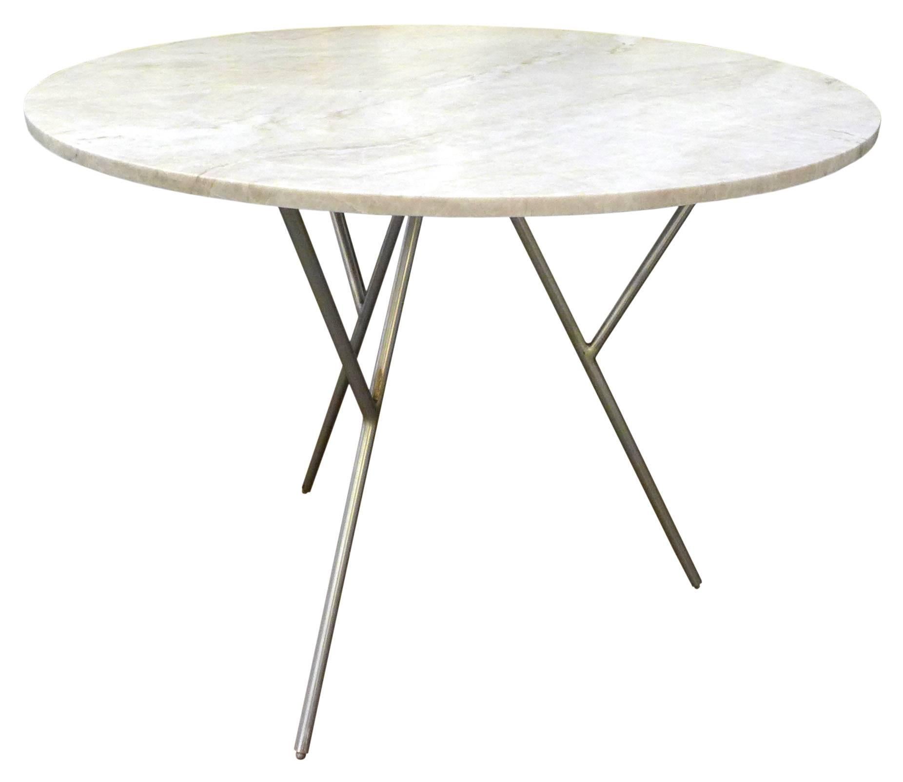 A fantastic travertine and steel dining table. A tripod base of welded, brushed steel; slender, splayed legs each with a jutting buttress for supporting a contemporary, round travertine tabletop. The base is beautifully constructed of heavy,