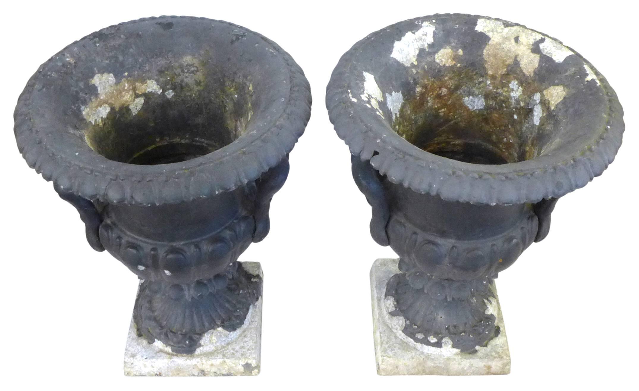 A stunning pair of neoclassical, decorative urns in zinc-clad cast-metal. Wearing a beautiful patina, mottled and oxidized from years of life outdoors; a 1940s American homage to 19th century European garden ornaments. Elegant and timeless, great