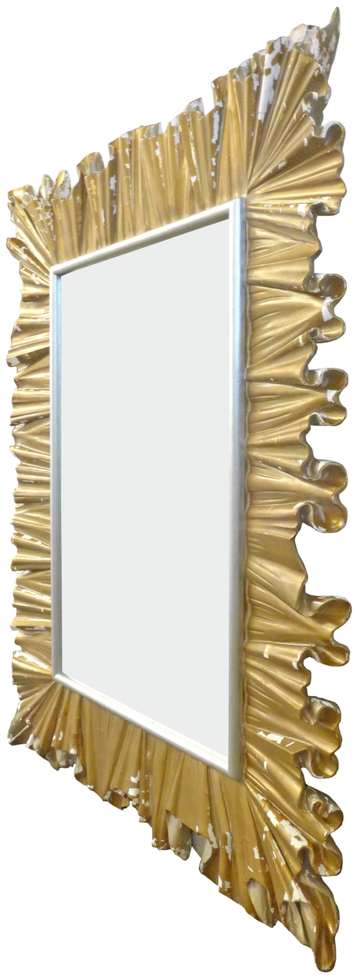 A spectacular and dramatic hand-carved-wood Italian mirror. An elegant, undulating form with impressive scale and decorative presence. An interesting, worn surface reveals hints of the base, wood structure, gesso, gilt and distressed painted