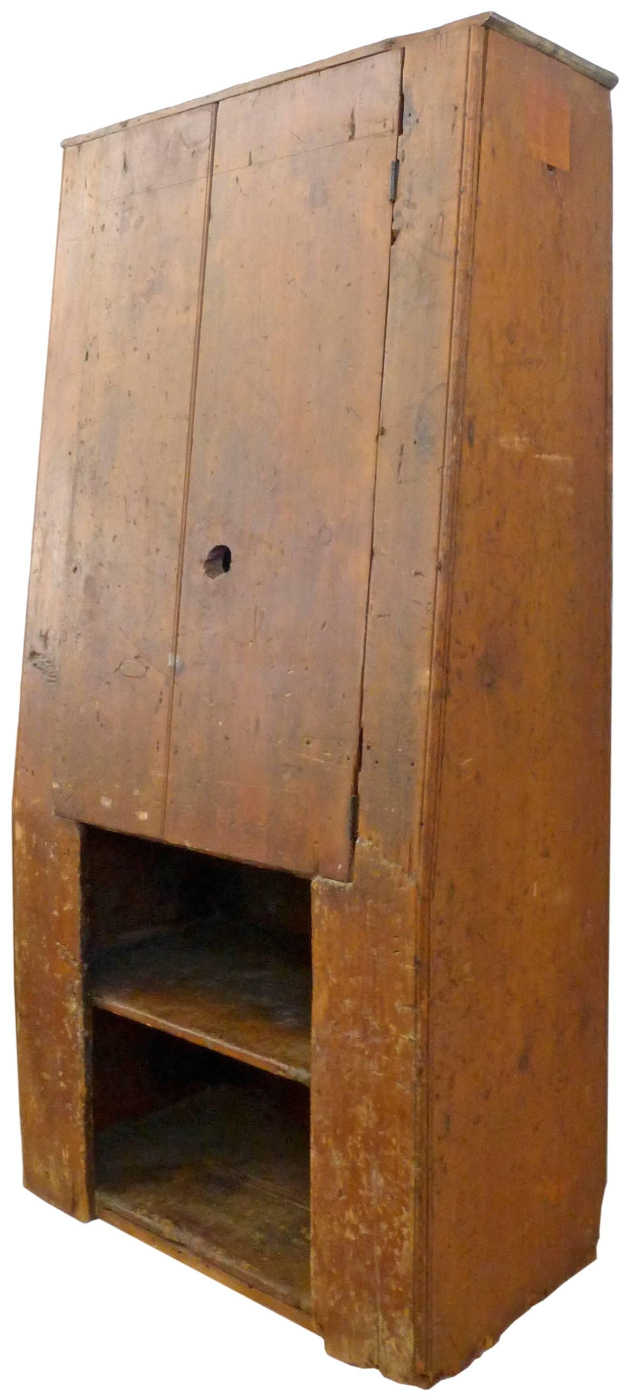 An unusual and architectural American Primitive cabinet from the mid-18th century. A beautiful and rarely-seen canted-front form in American pine. A special storage option hailing from Vermont with great character and lines. This cabinet would mix