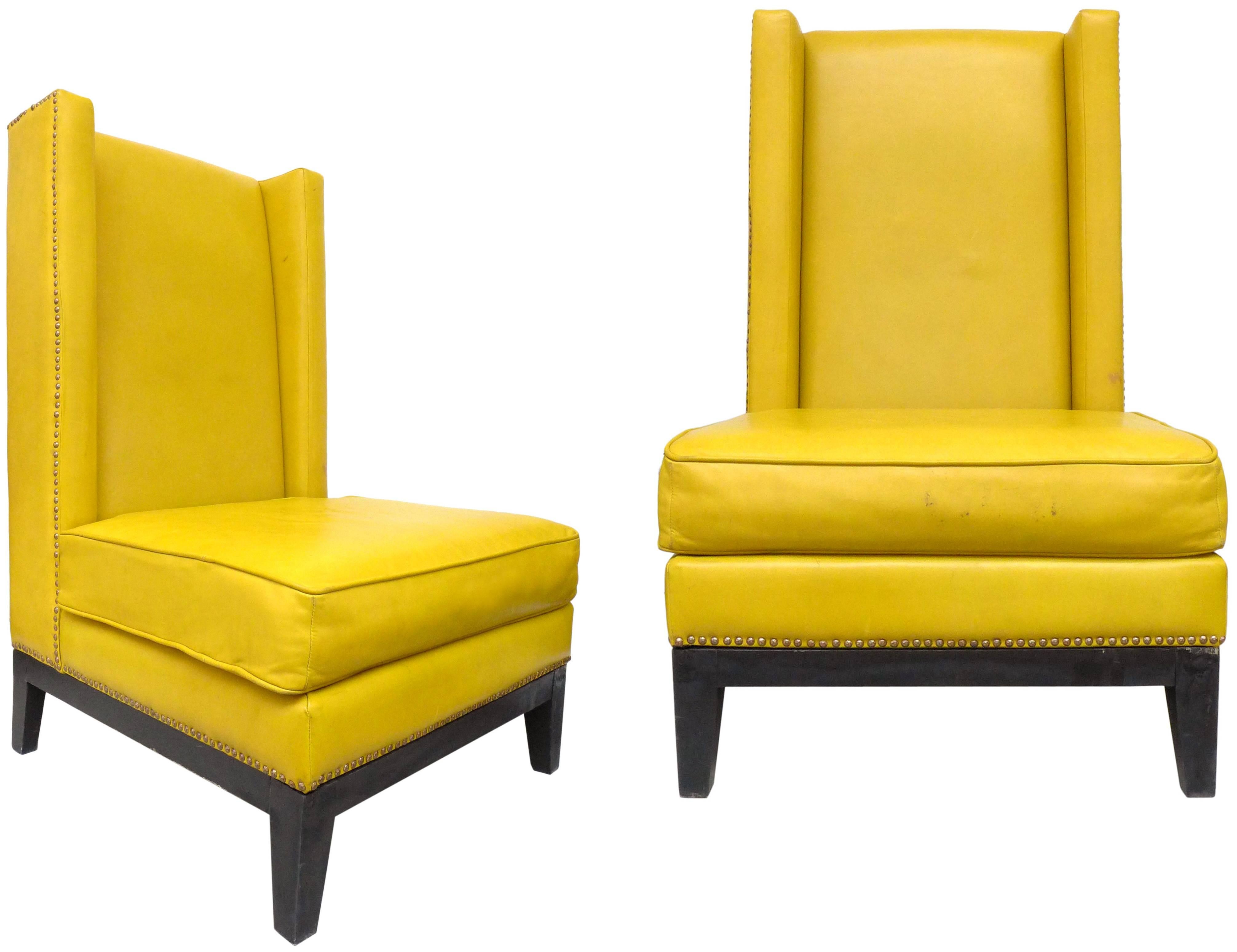 A fantastic pair of leather wingback chairs. Original mustard leather with brass-tacks detailing and ebonized wood base, a wonderfully streamined, modern version of this traditional form with clean lines, a notably deep, comfortable seat and