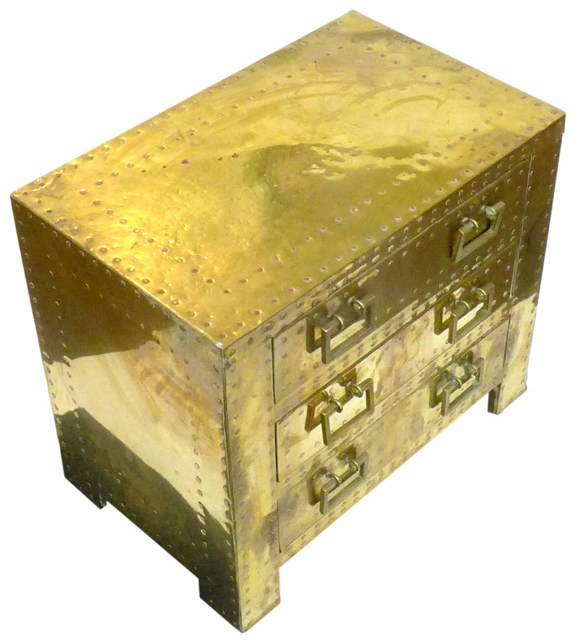 An exceptional pair of low, brass-clad chests of drawers by Sarreid. Fantastic, varied patination with warm blends of surface tones creating magnificent decorative character. Adorned with ornamentally-applied, functional rivets and original brass