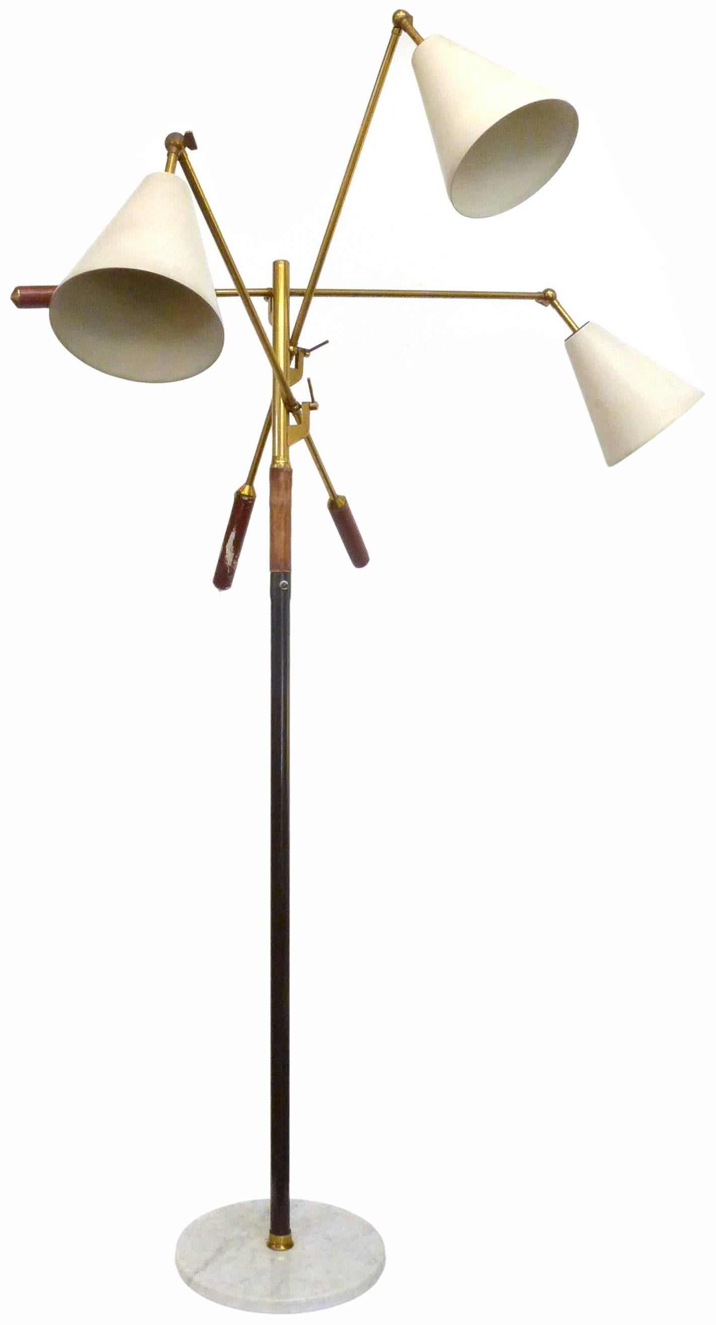 A beautiful and rare Triennale three-light floor lamp by Arredoluce, Italy. A brass shaft and adjustable, articulating arms with stitched, brown, pigskin handles and enamelled, cream metal shades; all seated in a round marble base. Wonderful,