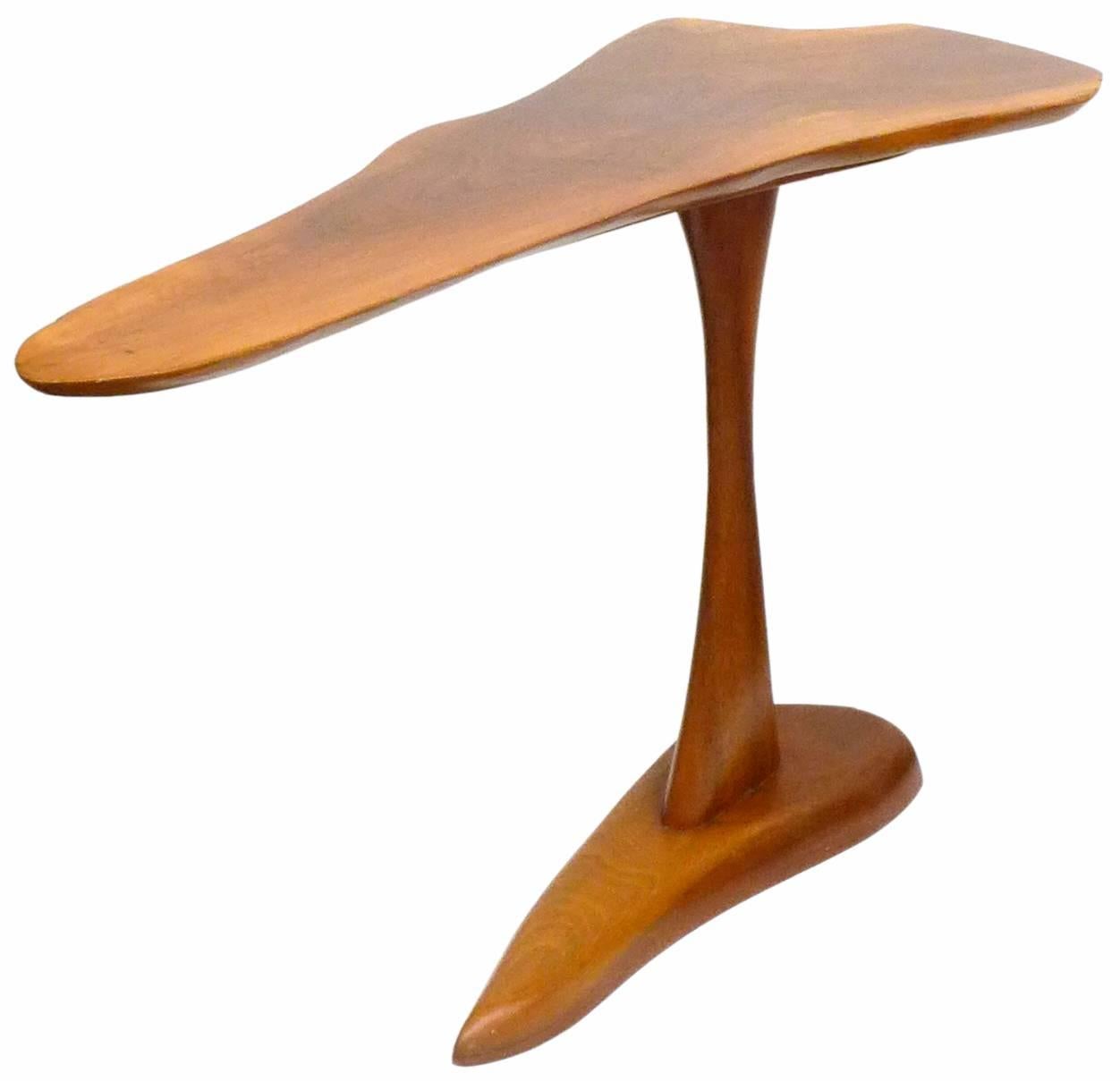 An elegant and unusual organic wood side table. A stunning, slight form, a top with fully free-edge perimeter sitting upon a gracefully tapering stem and top-mimicking base. A deep, honey hue with wonderful woodgrain revealed throughout. Signed