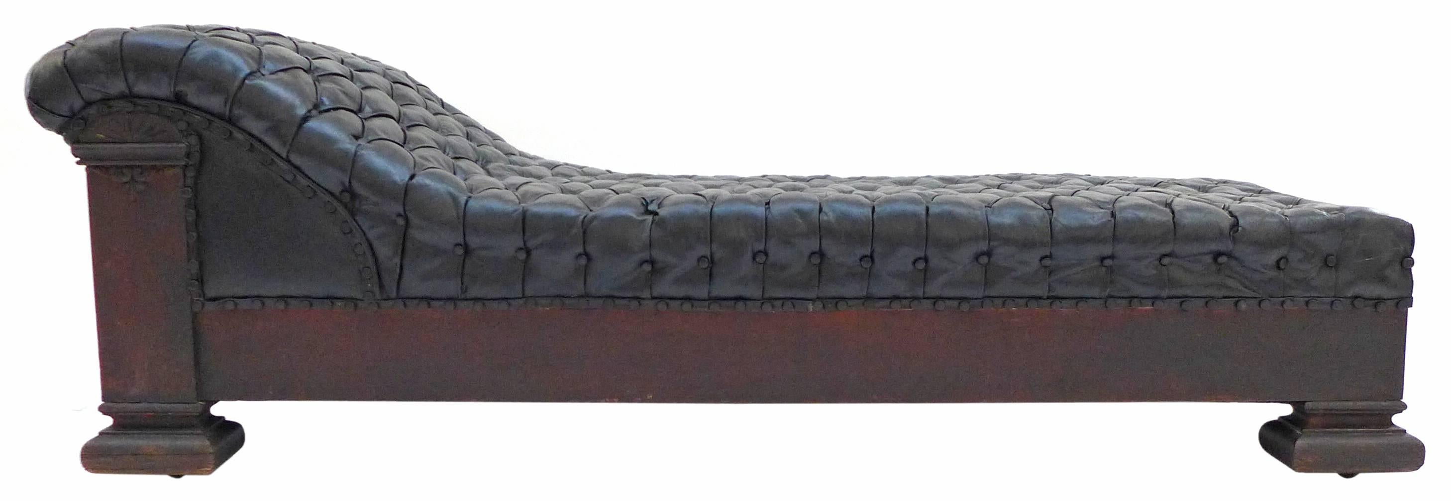 An exceptional, tufted, black leather and oak chaise longue. Evoking the dawn of psychoanalysis, an extraordinary seating option of great detail perfectly aged, tufted leather; wood wearing great age and dark patina; subtle applied ornamental