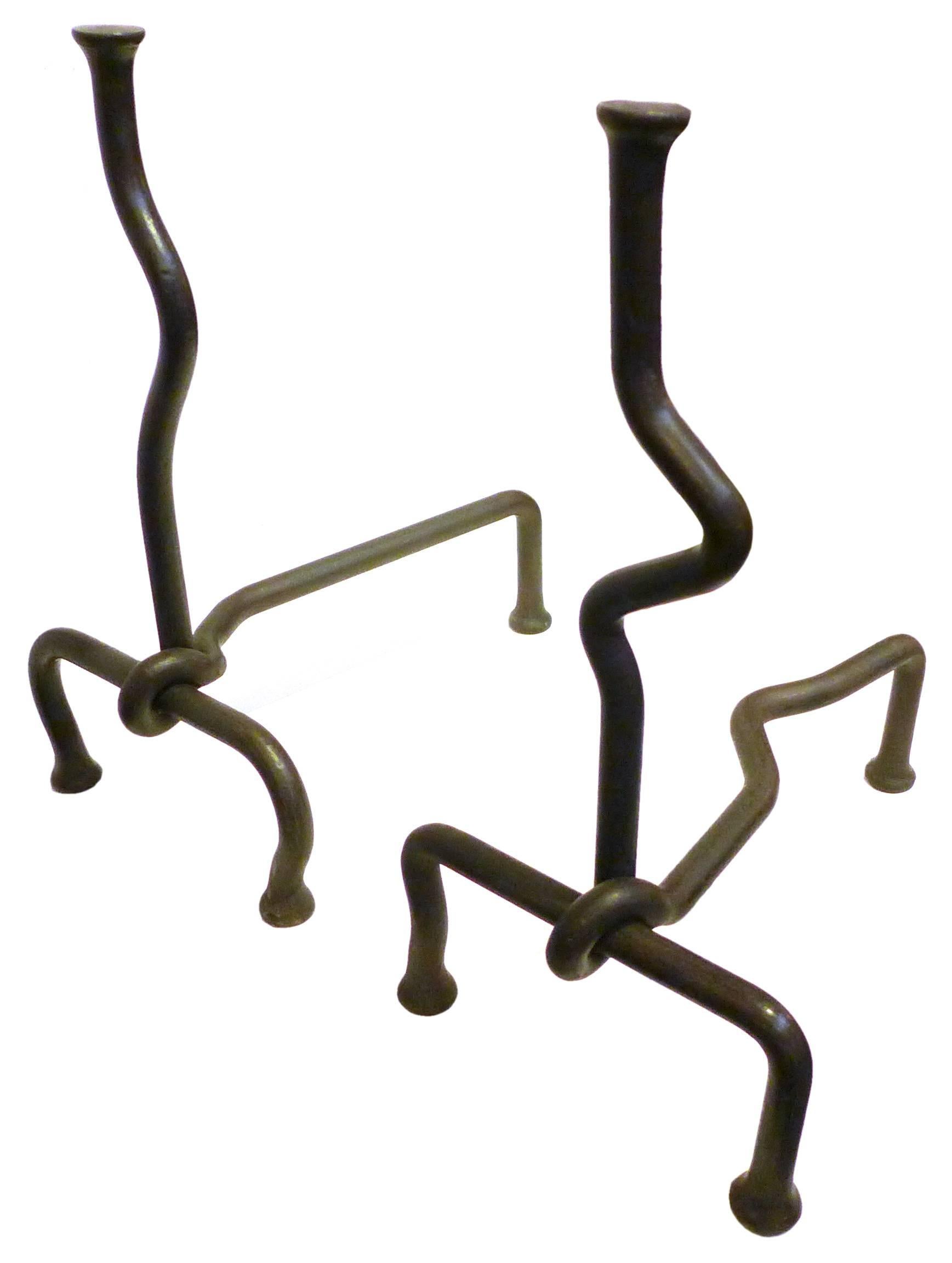 A playful pair of intentionally mismatched, hand-wrought andirons. Beautifully simple, animated, sculptural forms, each of one squiggled, iron rod twisting around another. Unexpectedly and delightfully dynamic for both the material and use,