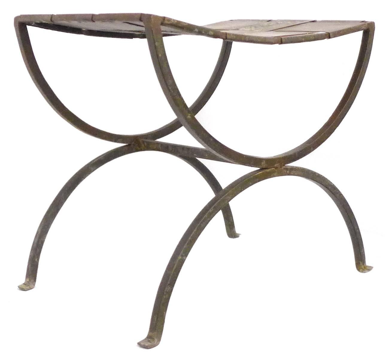 A handsome pair of wrought iron stools.  An elegant, classic form of arched, splayed legs with turned-out feet; mirror-image, arched seat-supports; graphically simple and alluring.  An interesting and unusual seat of woven, wide-slat sheet metal. 