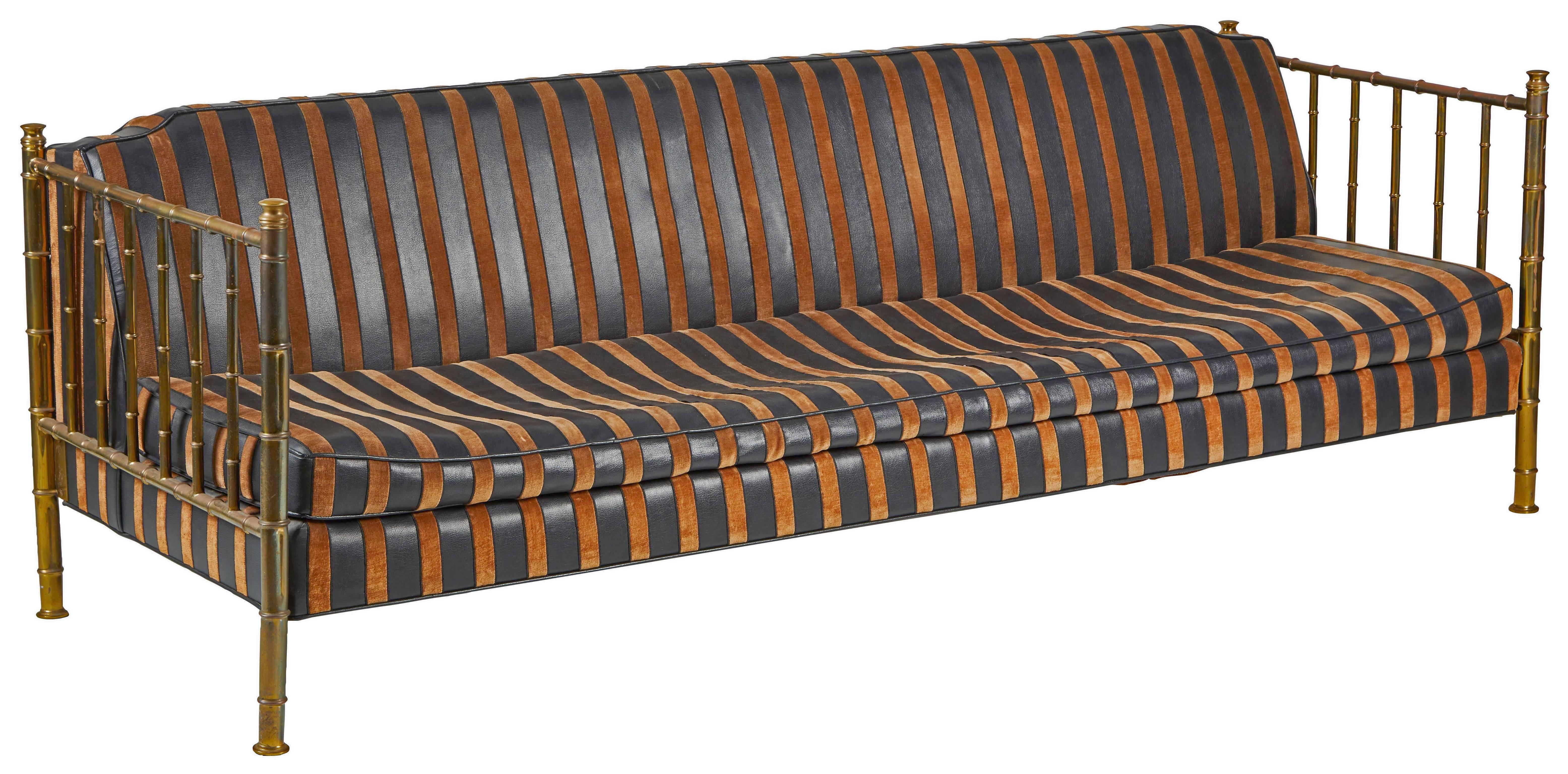 A fantastic brass, faux bamboo sofa by Mastercraft.  Nearly 8' in length, a striking, highly decorative piece wearing the original black/copper-striped leatherette/velvet upholstery.  Including two original, tufted bolster pillows.  Wonderful patina