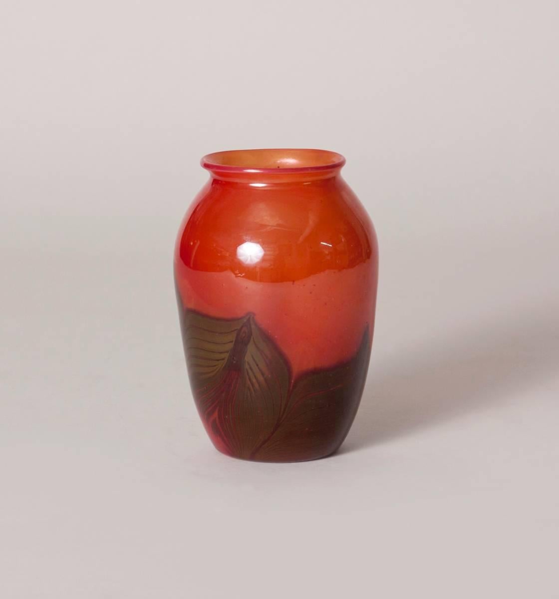 A Tiffany studios favrile glass paperweight vase with red body and olive leaf decoration, signed.