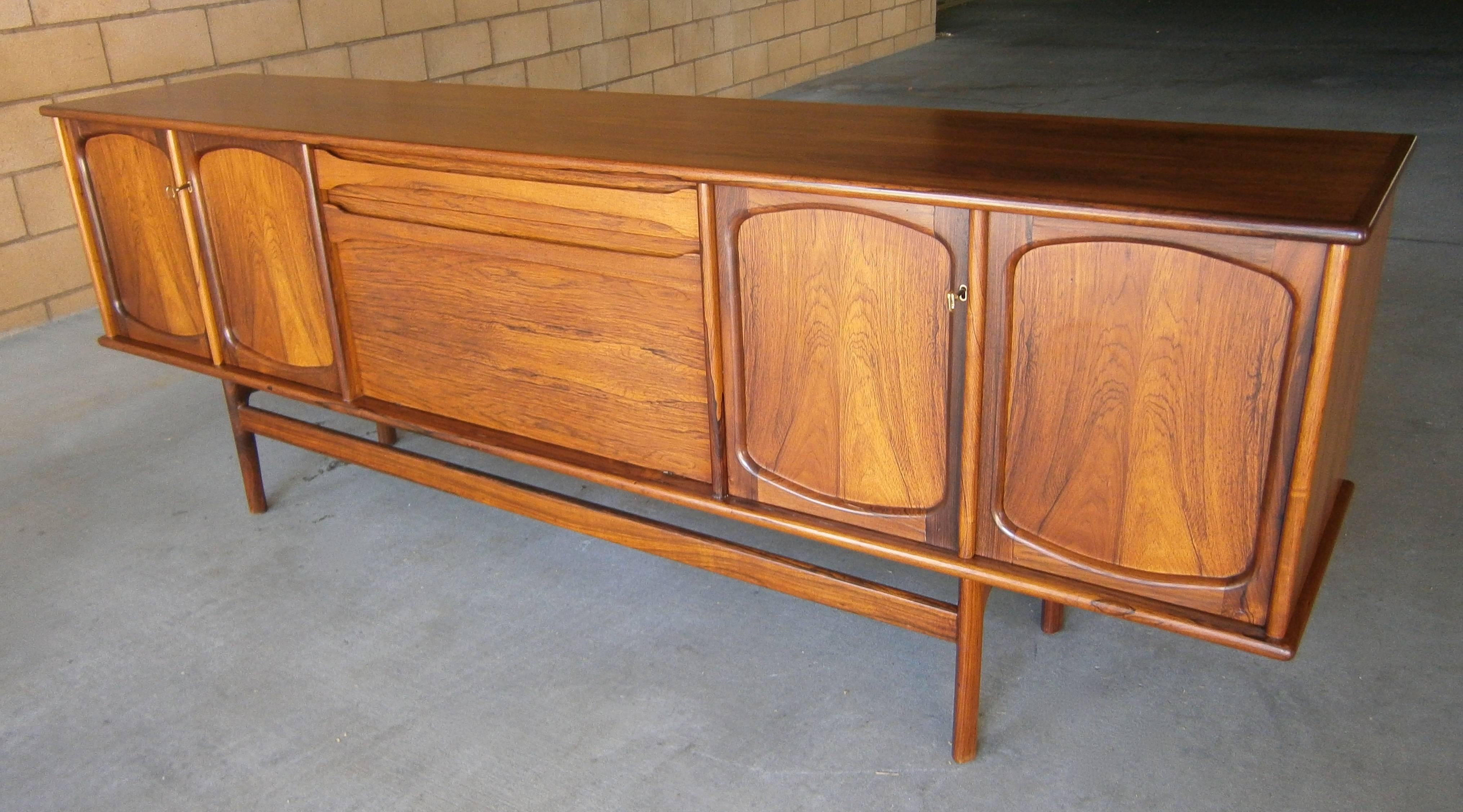 A gorgeous and outstanding 1960s Norwegian figured rosewood sideboard, attributed to furniture designer Gerhard Berg. Pairs of doors flank a central fold-down bar and drawer section. The cabinet retains it original rosewood veneered interior shelves