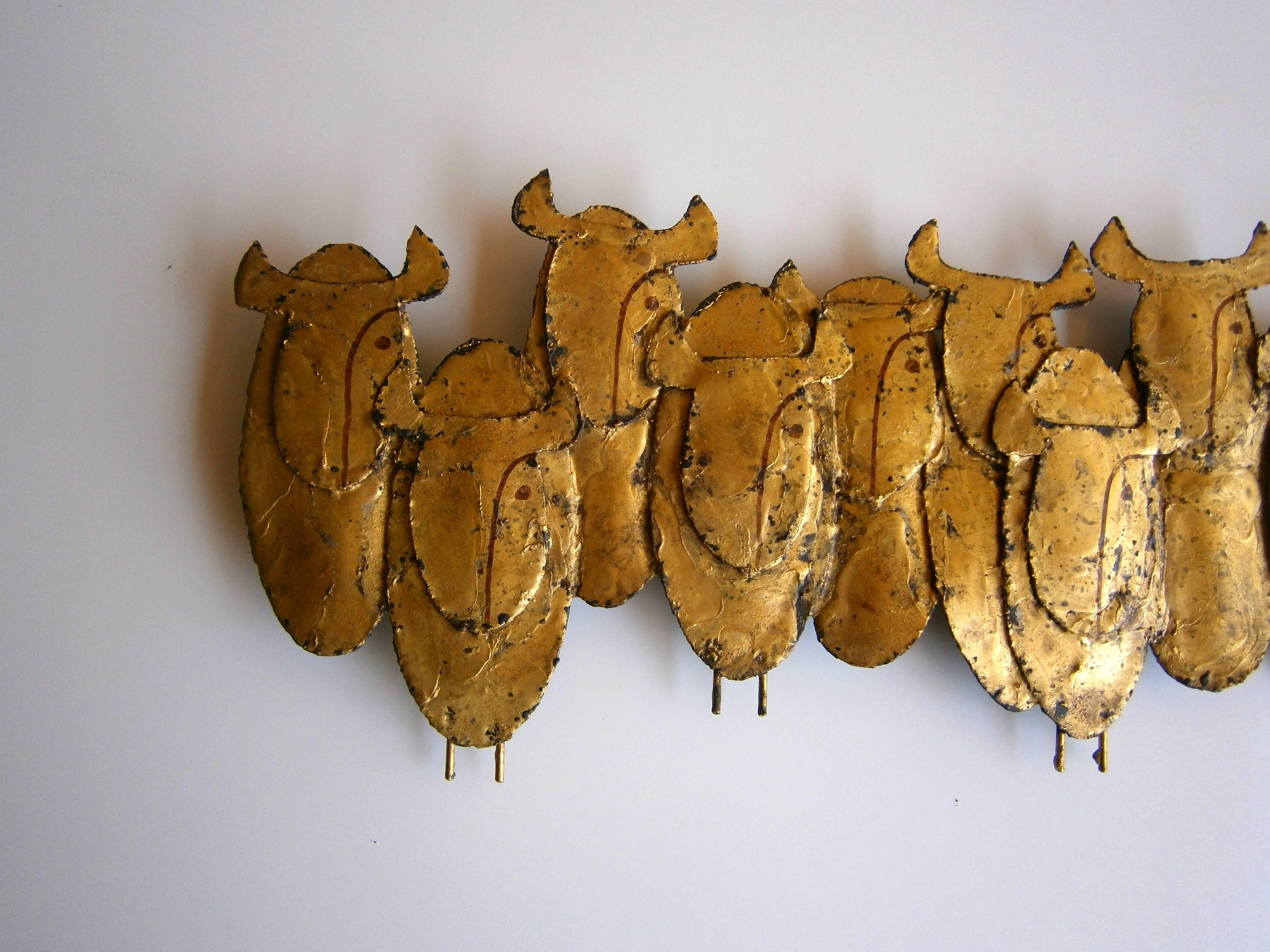 A rare gilded steel wall sculpture depicting a stylized group of 