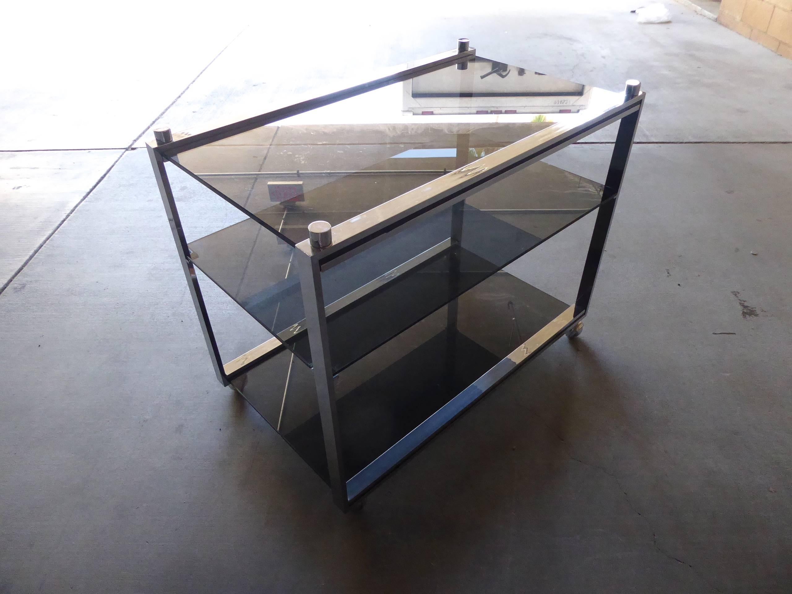 A chrome-plated steel and smoked glass three-tier rolling bar cart from the box line by Charles Hollis Jones. The cart was acquired from a home in Palm Desert, California and Mr. Jones has verified that it was made in 1968. It is completely original