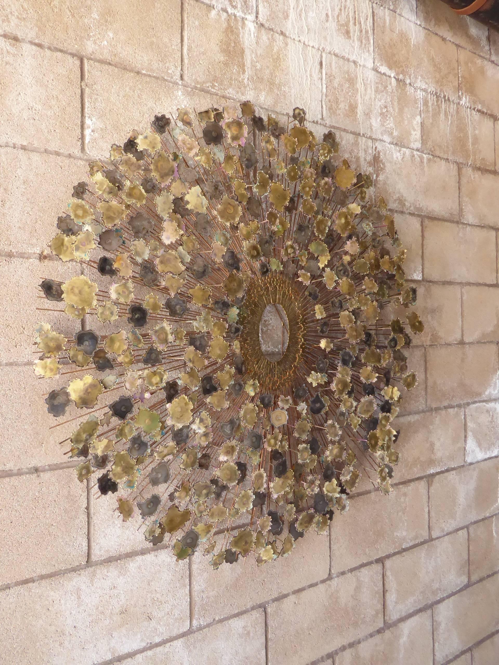 An oval-shaped mixed metal wall sculpture attributed to American artist William Friedle from the 1960s. This glamorous wall sculpture is a departure from the typical Brutalist starburst form and the torch-cut 