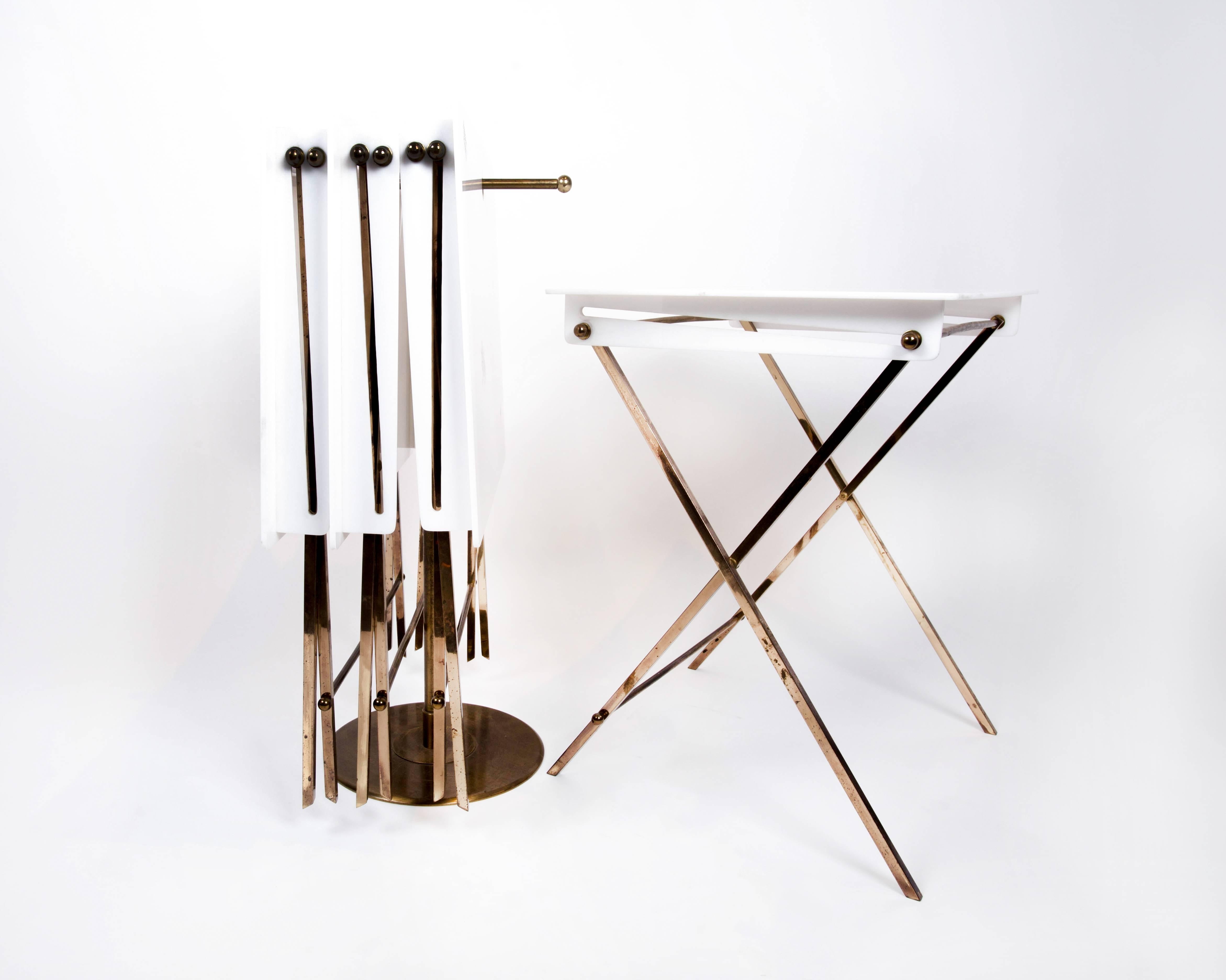A set of 4 white Lucite and brass collapsable television snack tables on a brass stand designed by Charles Hollis Jones. Circa 1970s.  Sets of these tables are very difficult to obtain. This set is offered in very good, vintage condition with