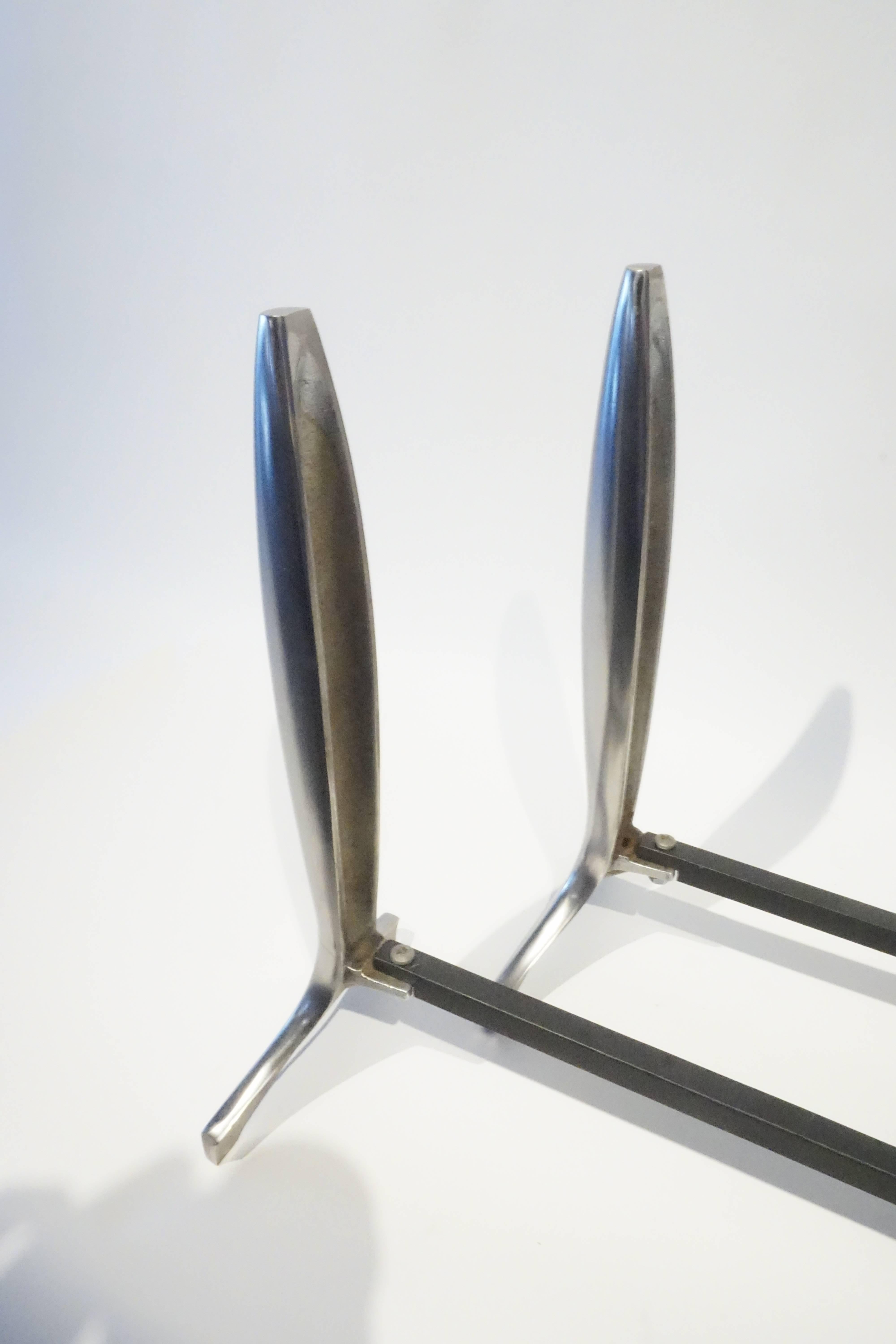 A pair of American modernist polished aluminum andirons from the 1940s. The form of the andirons is referential to Industrial design and rocket forms that were avant-garde after the deco period.