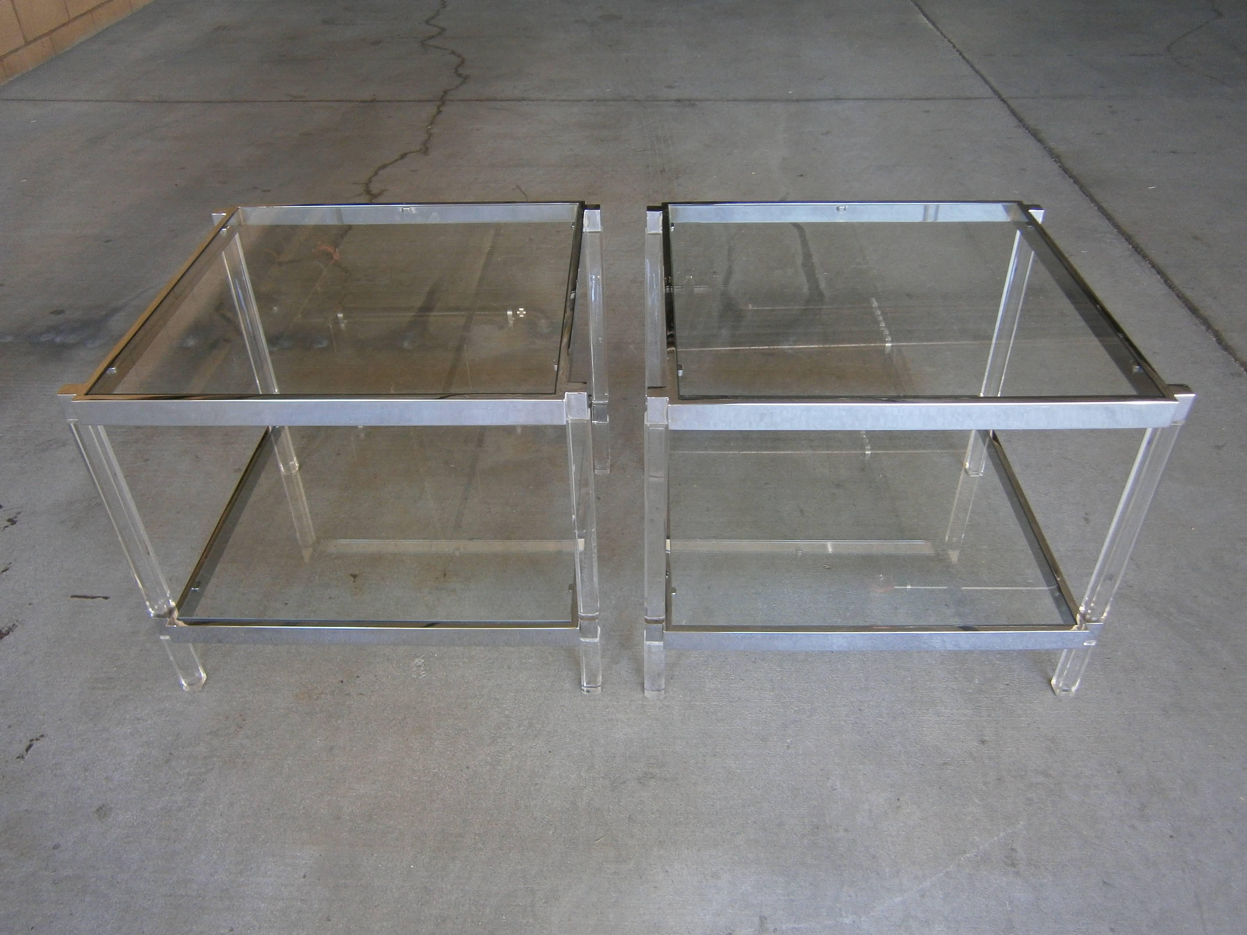 An pair of chromed steel two-tier side tables designed by Charles Hollis Jones for his Metric Line in the early 1970s. Each of the tables has Lucite legs that support chrome plated metal frames with inset glass shelves. With the exception of the new