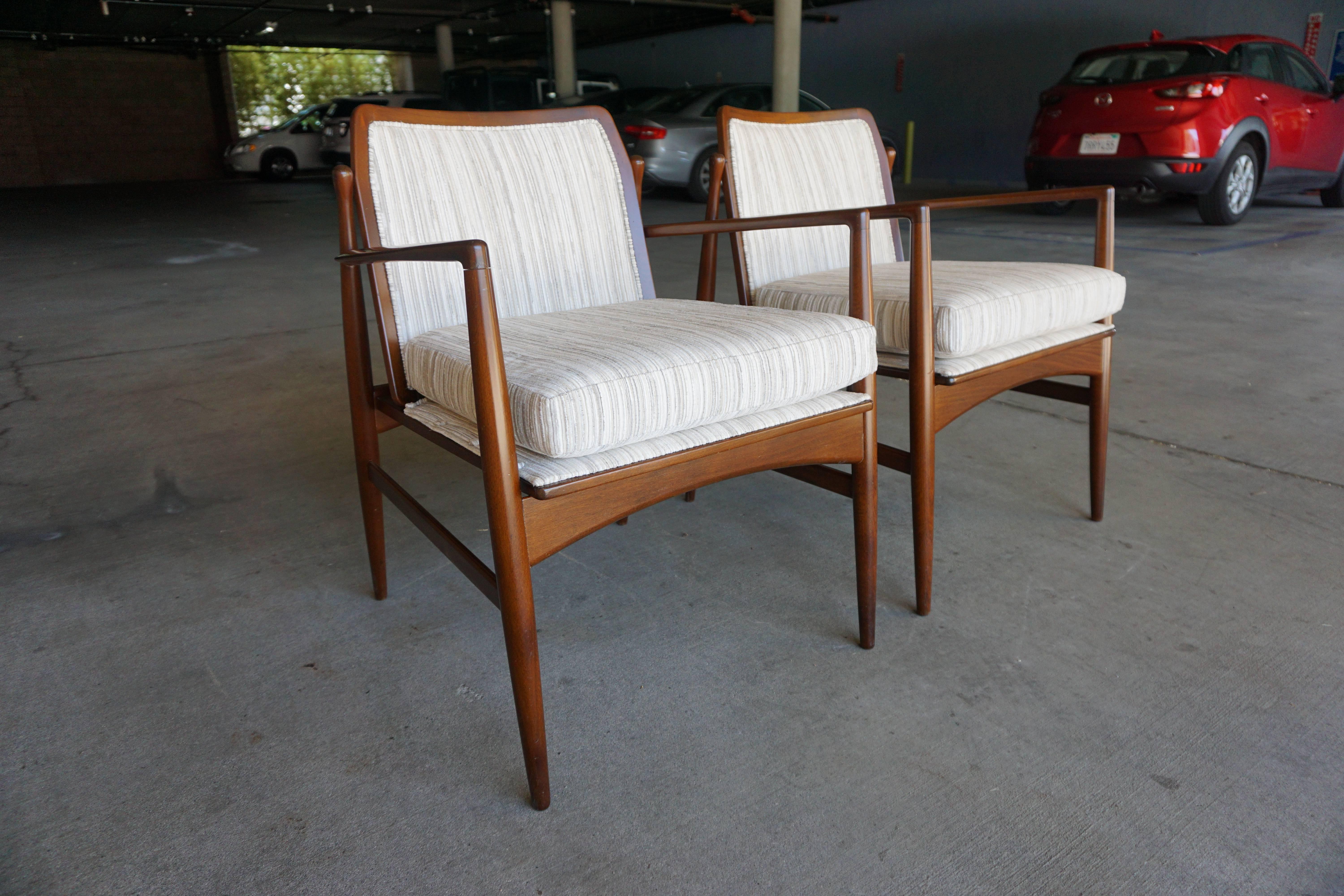 A distinctive pair of mahogany framed Danish modern armchairs from the 1960s. The handsome pair has been newly reupholstered in a high quality tan/gray striped fabric.