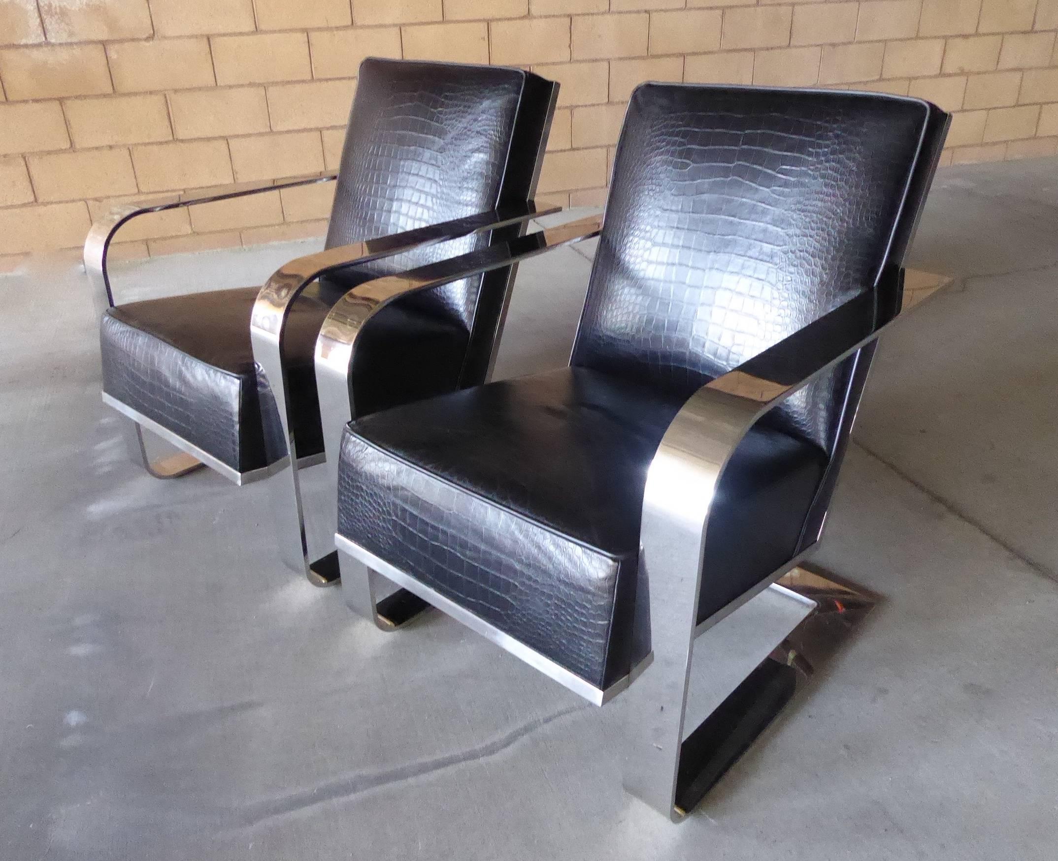 A pair of Art Deco inspired lounge chairs made by Ralph Lauren Home. The chair frames are made of solid nickel-plated steel and are upholstered in an embossed crocodile patterned black leather. The chairs are substantial in size and weight and offer