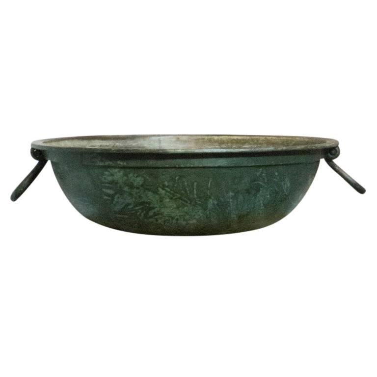 Cast bronze with a patina of age and wear, this basin resembles a low bowl planter and features attractive flaring handles. Standing at 8.5 inches tall and 28 inches in diameter this bronze basin will blend nicely with your garden antiques and