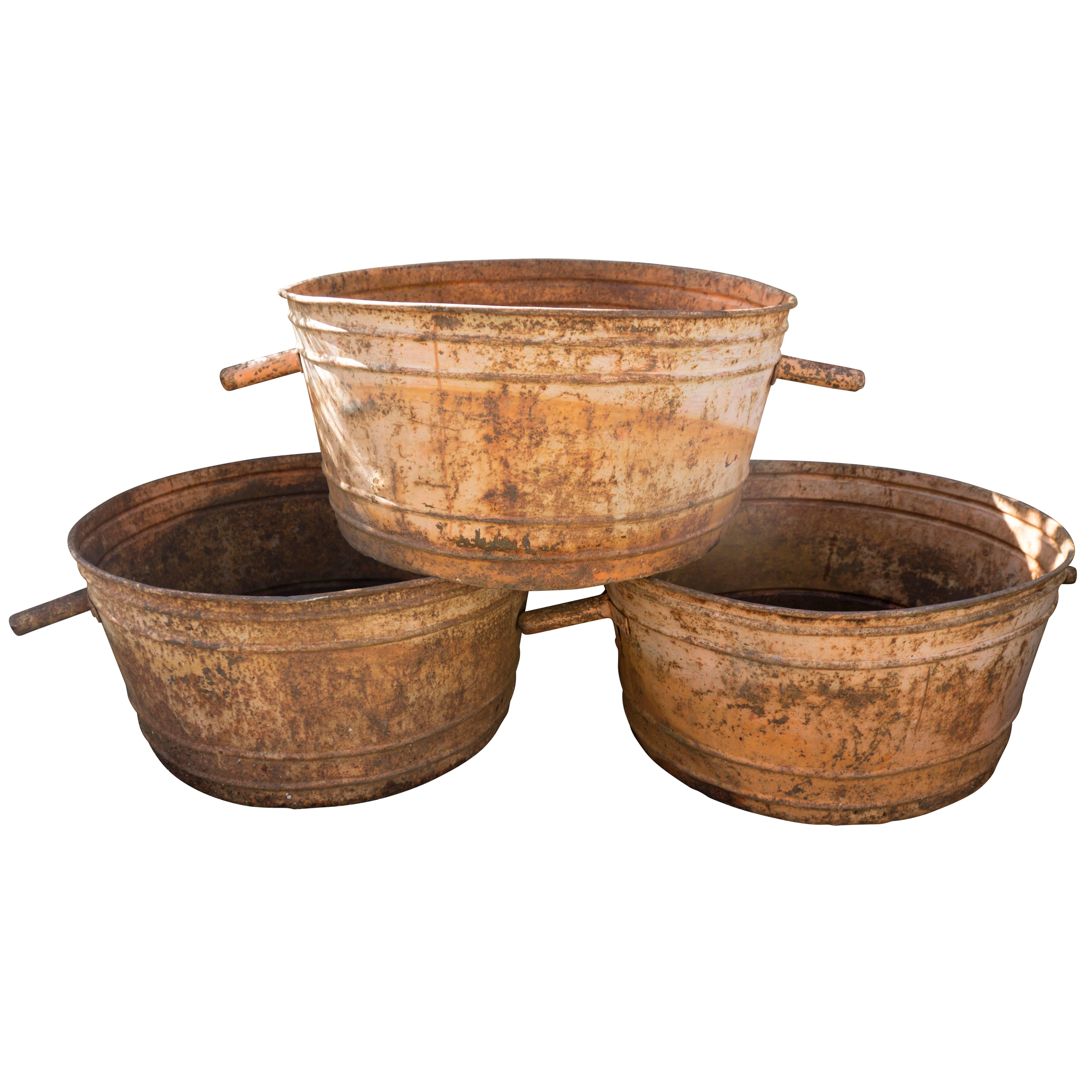 Available individually or in a set of up to three while in stock. These copper tubs make excellent use as planters. Appearing slightly dented and misshapen with orange rust patina along with unique small handles. These copper tubs incredibly