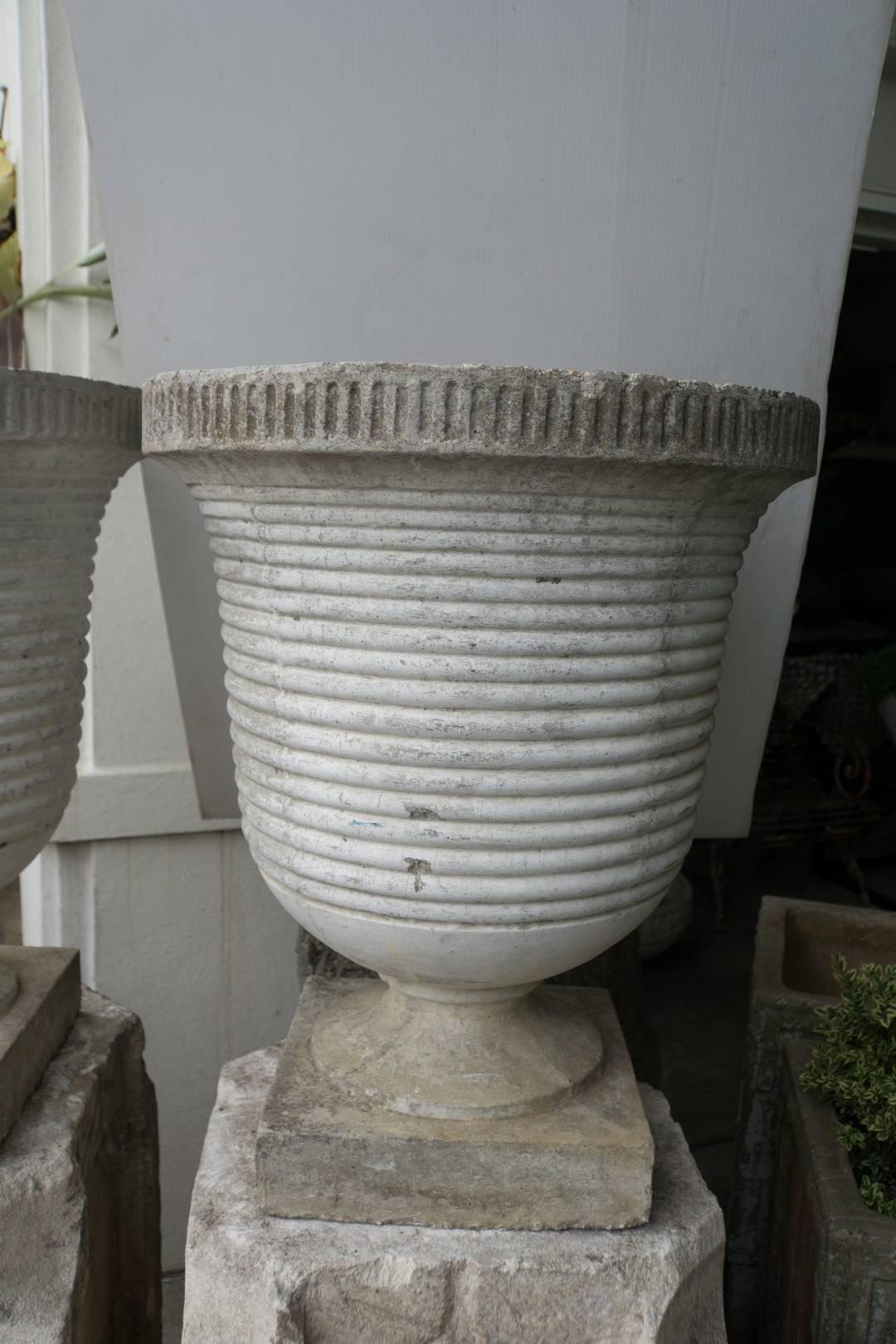 Pair of footed cast stone deco planters with horizontal ribbing, circa 1940, France. Measures: 22'' D x 27'' H. $8,500.00 pair only.